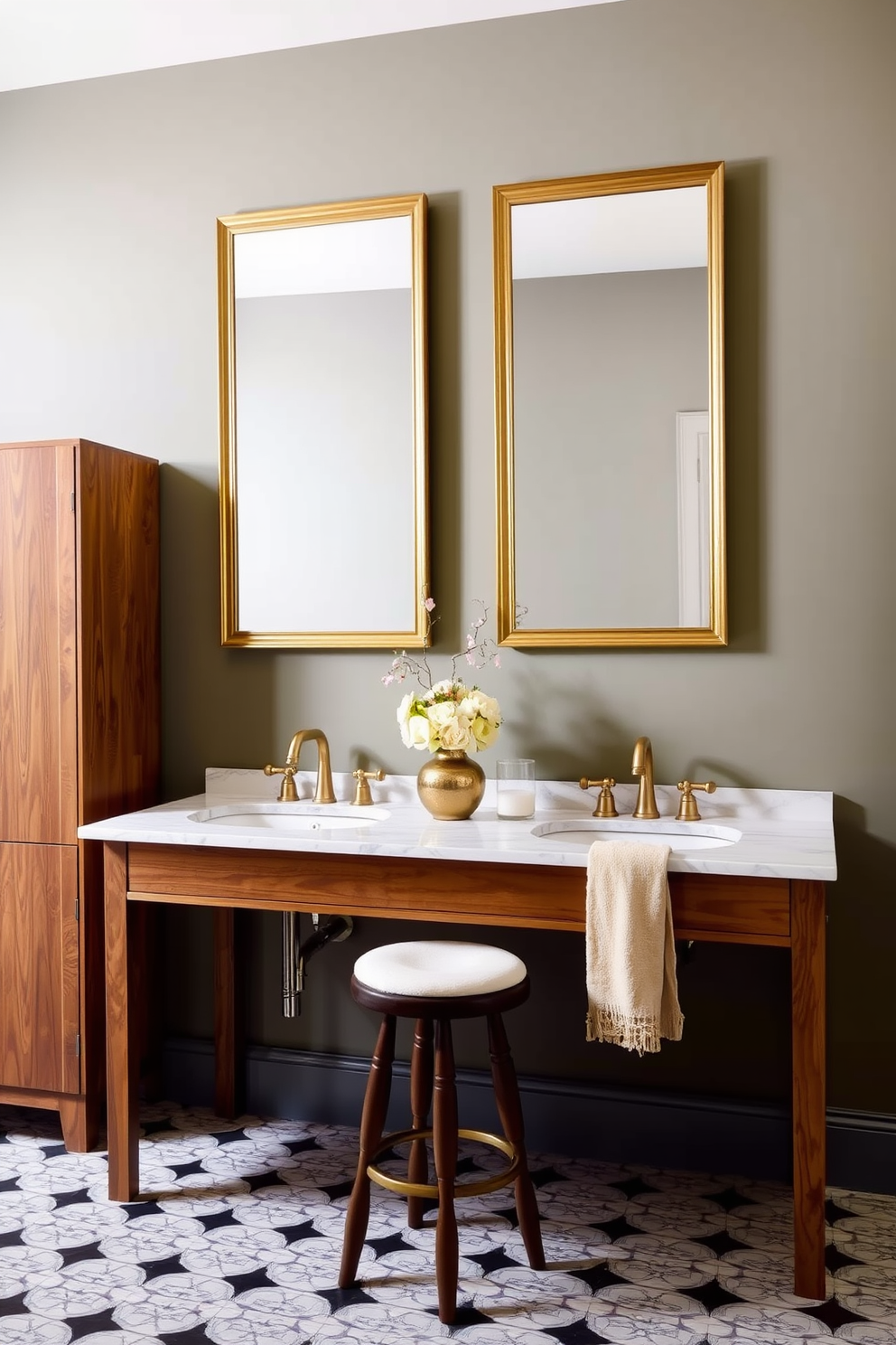 A sophisticated bathroom setting featuring a wooden vanity with a marble countertop and two sinks installed. Above the countertop, two rectangular mirrors with gold frames hang side by side, enhancing the elegance of the space. To the left of the vanity, a tall wooden cabinet provides ample storage. The walls are painted in a muted green shade, while the floor showcases a white and black patterned tile. A decorative vase with flowers adds a touch of color to the countertop, and a beige towel hangs from one of the sink faucets. A small stool for seating is positioned nearby, offering a functional and stylish addition to the design.