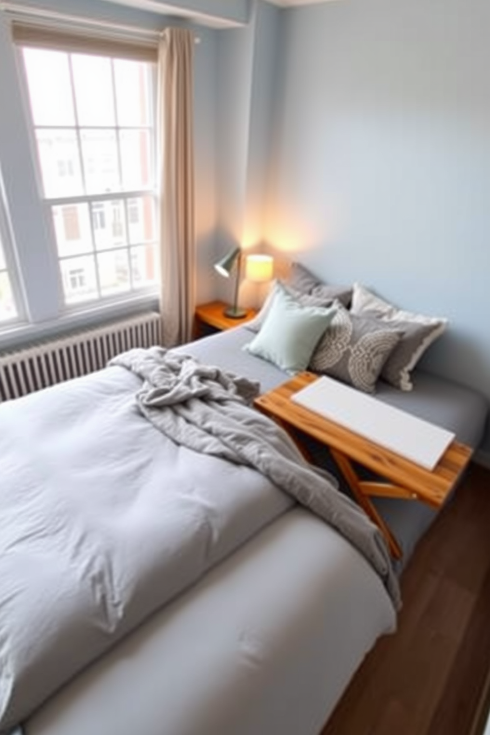 A cozy apartment bedroom featuring a sleek desk positioned near a window for an ideal workspace. The bed is adorned with soft linens and plush pillows, while a stylish rug adds warmth to the hardwood floor. The walls are painted in a calming light gray, complemented by framed artwork that adds a personal touch. A bedside table holds a modern lamp, creating a perfect reading nook beside the bed.