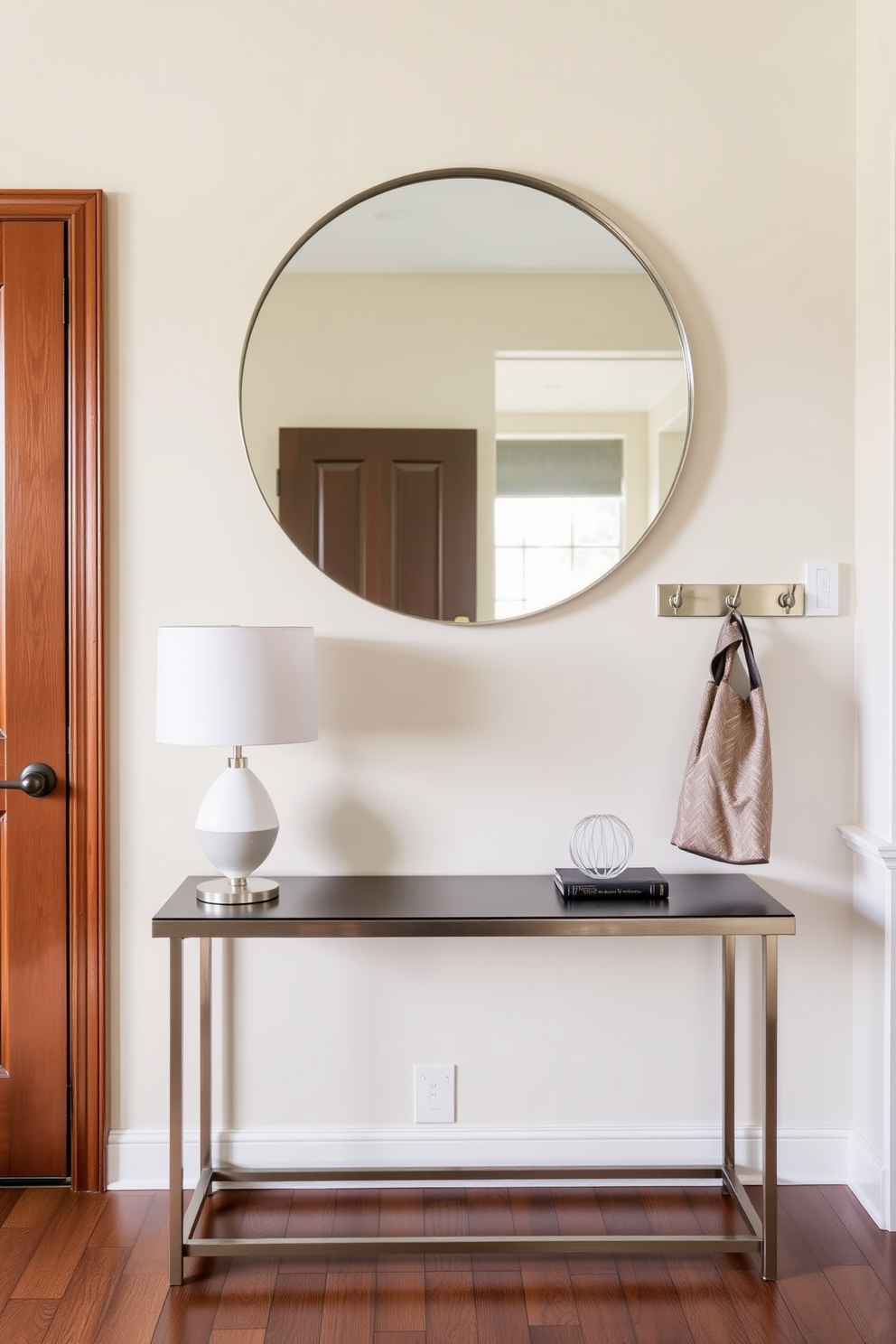 A warm and inviting entryway features a sleek console table against the wall adorned with a stylish table lamp. Above the table, a large round mirror reflects the space, while a set of hooks in a brushed nickel finish holds coats and bags.