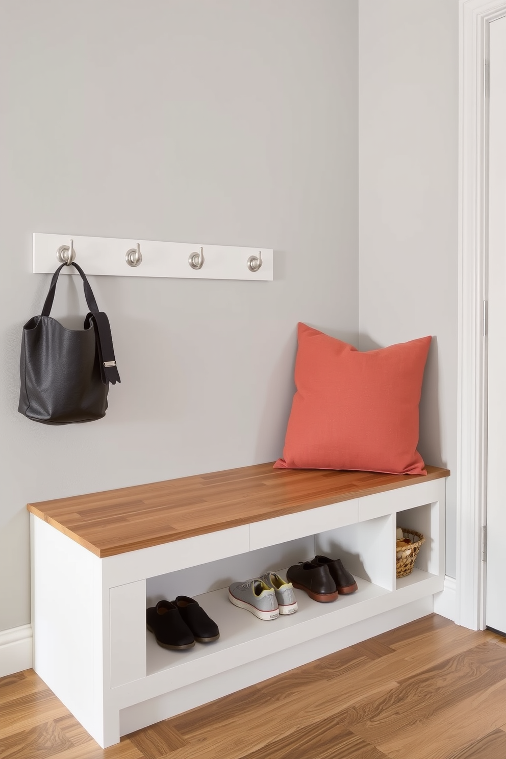 A stylish apartment entryway featuring integrated shoe storage beneath a sleek bench seating area. The walls are adorned with a soft gray paint, and a warm wood finish highlights the bench while providing a functional space for shoes.