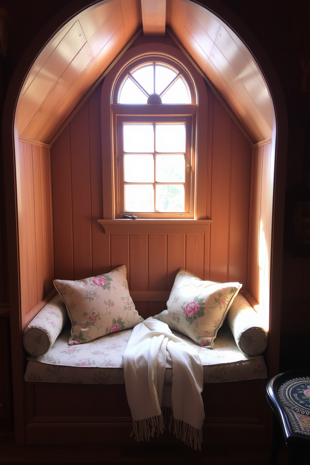 A cozy vintage-style window seat is nestled beneath a charming attic window. It features plush cushions in floral patterns and a soft throw blanket, inviting relaxation and comfort. The walls are adorned with warm wood paneling, creating a rustic yet elegant atmosphere. Natural light pours in through the window, illuminating the space and highlighting the surrounding decor.