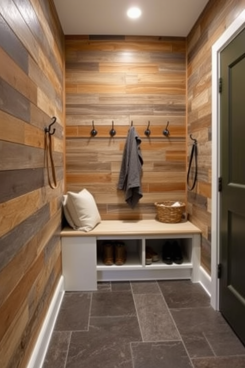 A cozy mudroom with a mix of textures. The walls are clad in reclaimed wood, while the floor features a durable slate tile, providing a practical yet stylish foundation. A built-in bench with soft, cushioned seating contrasts with the ruggedness of the wood. Hooks for coats and baskets for shoes add functionality and charm, creating an inviting entryway.