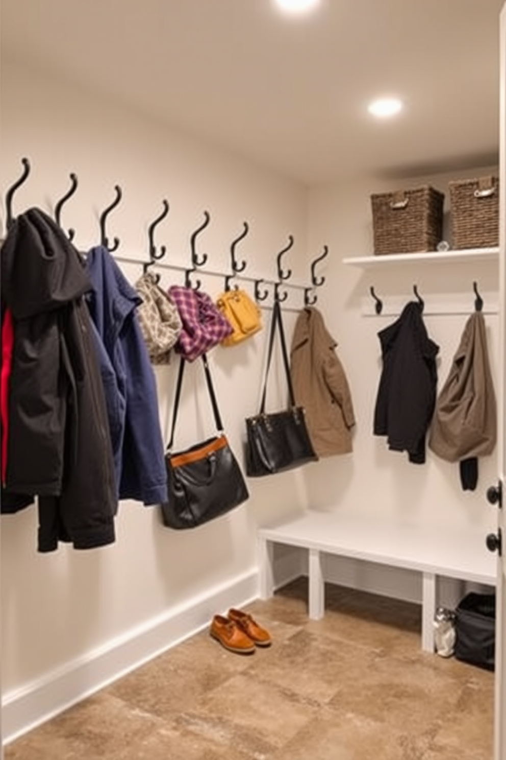 A functional and stylish basement mudroom features a series of wall hooks arranged in an organized manner for hanging coats and bags. The space is designed with durable flooring and ample storage solutions, creating an inviting and practical entryway.