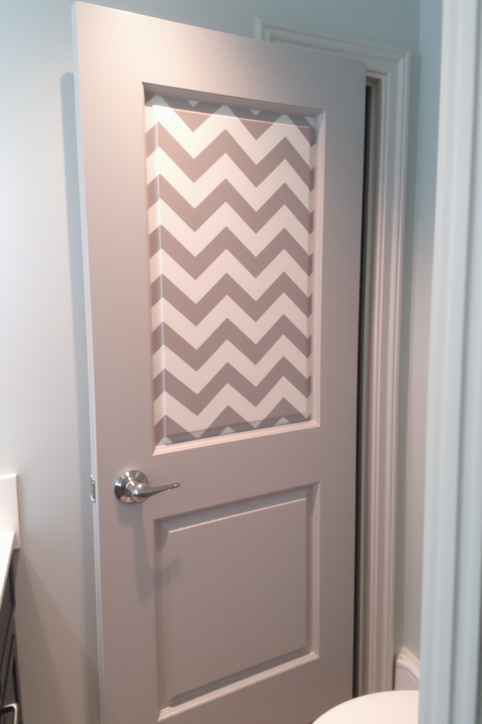 A stylish bathroom door features a chevron pattern that adds a modern flair to the space. The door is painted in a soft gray color, complementing the overall aesthetic of the bathroom.