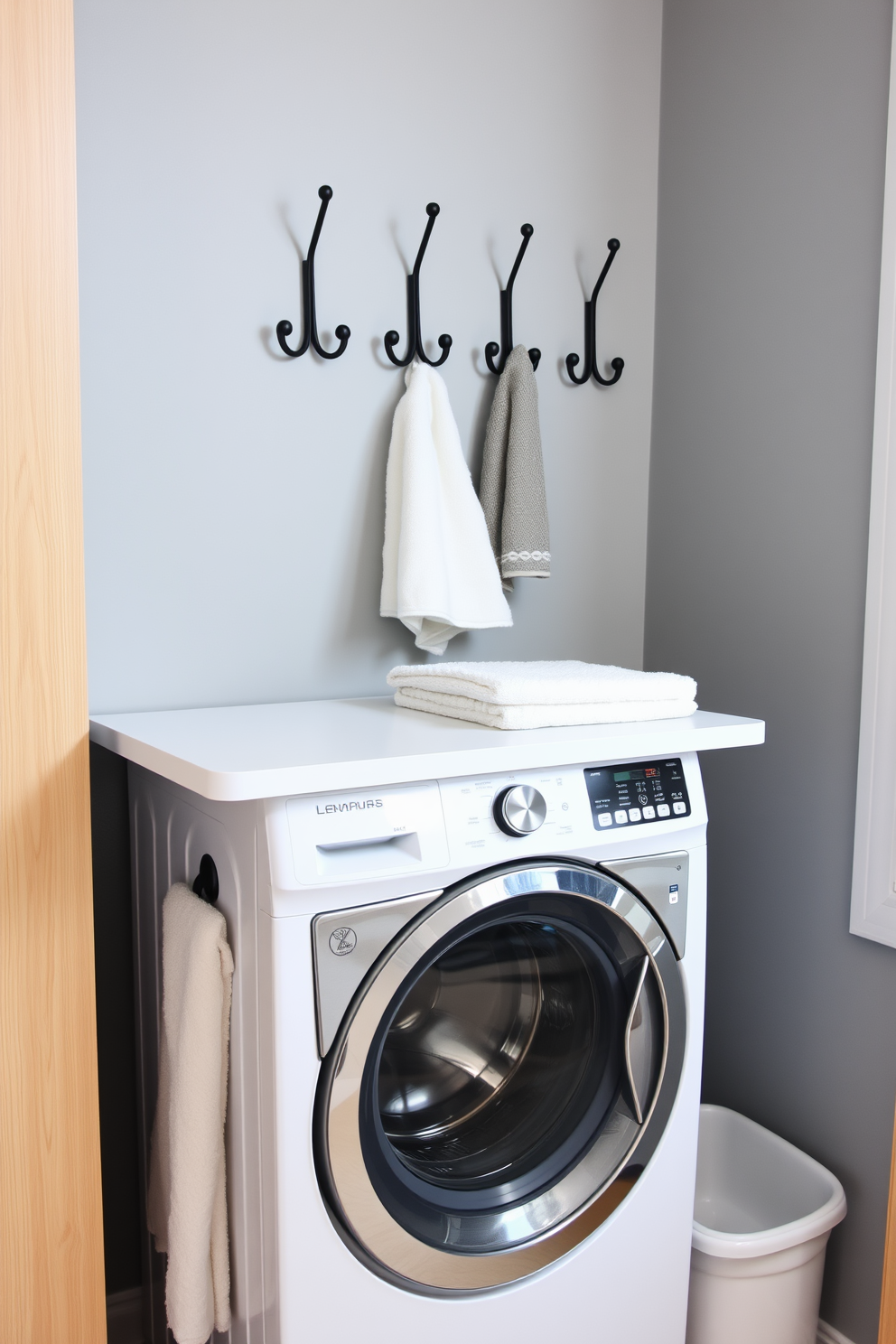 Create a stylish laundry room that incorporates decorative hooks for hanging items. The walls are painted in a soft blue color, and there are open shelves above the hooks displaying neatly folded towels and laundry essentials. Include a functional yet aesthetically pleasing laundry area with a combination washer and dryer. The space features a countertop for folding clothes, and decorative hooks are mounted nearby for hanging garments and accessories.