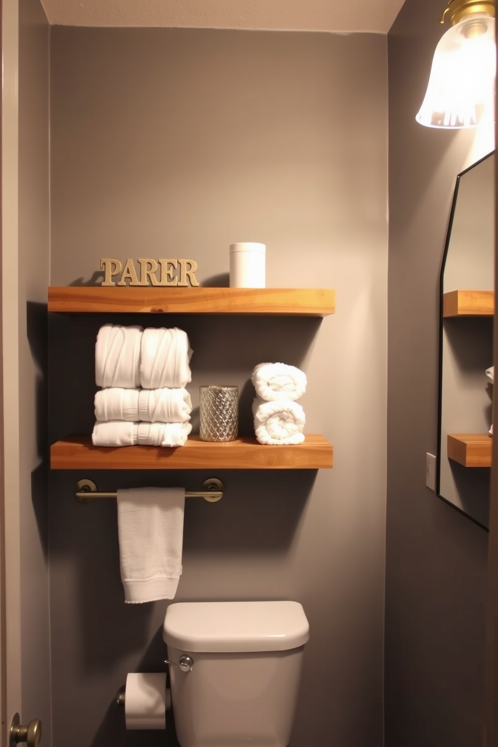 A stylish bathroom powder room features open shelving made of reclaimed wood, showcasing neatly arranged towels and decorative items. The walls are painted in a soft, warm gray, creating a cozy atmosphere complemented by a chic pendant light hanging above.