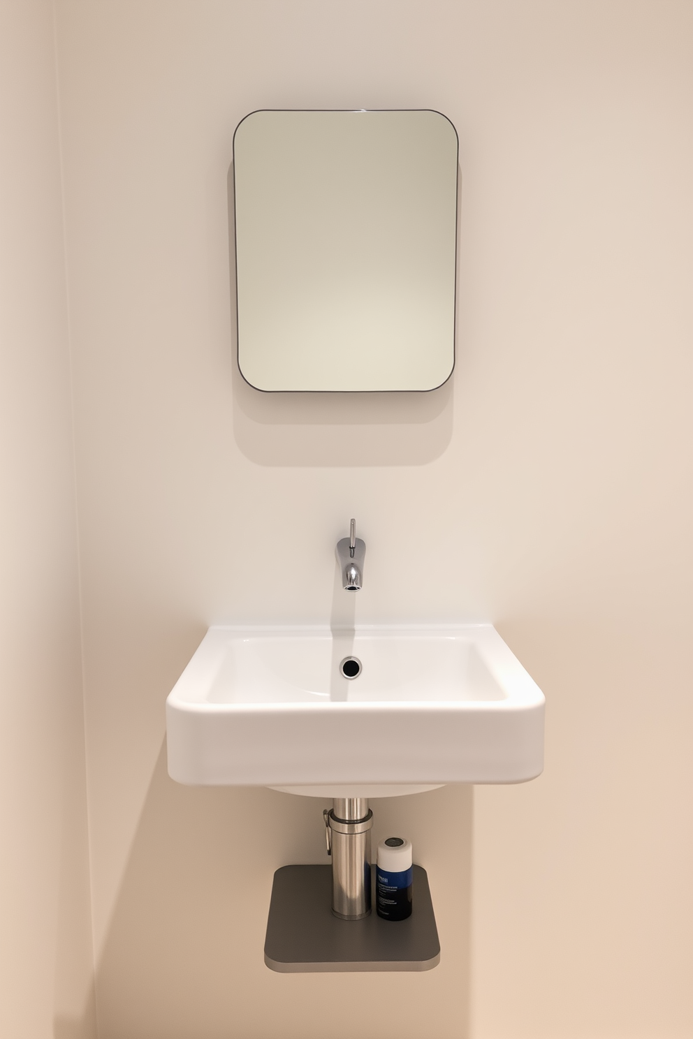 A minimalist wall-mounted sink is designed for small spaces, featuring clean lines and a sleek silhouette. The sink is complemented by a simple, understated faucet and a compact mirror above it, enhancing the sense of openness in the room. The walls are painted in a soft, neutral tone to create a calm atmosphere. Below the sink, a small shelf provides space for essential toiletries while maintaining a clutter-free look.