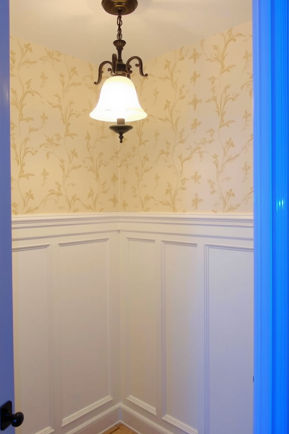 A classic bathroom featuring elegant wainscoting that adds a touch of sophistication. The walls are painted in a soft cream color, complementing the white wainscoting that runs halfway up. Above the wainscoting, the upper wall is adorned with a subtle floral wallpaper that enhances the traditional aesthetic. A vintage-style light fixture hangs from the ceiling, casting a warm glow over the space.