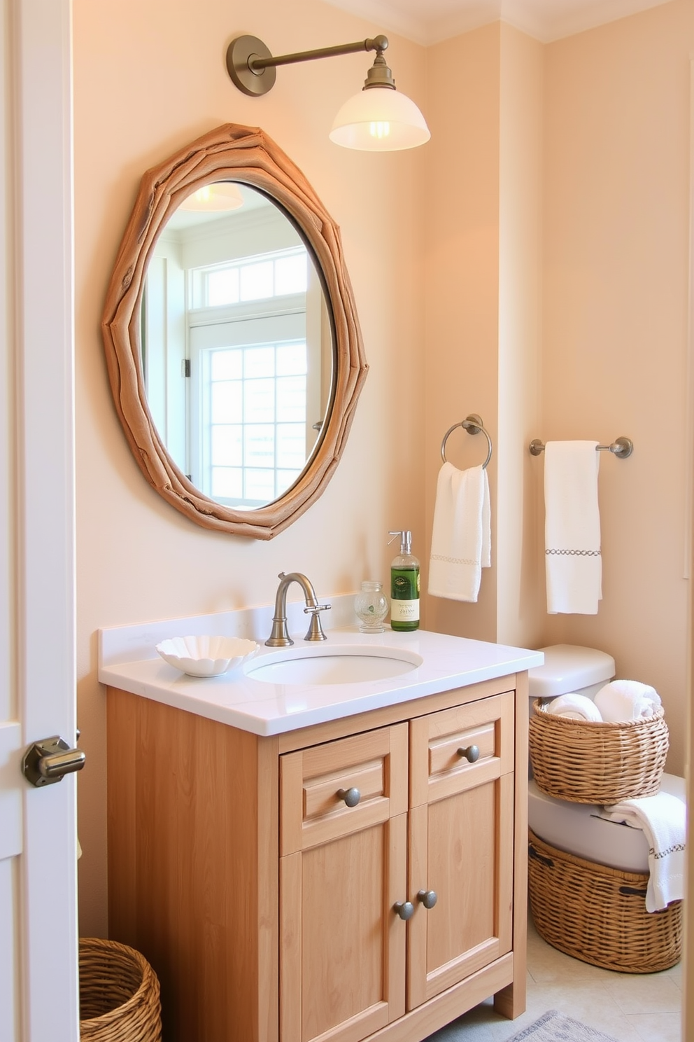 A serene beach bathroom setting featuring sandy beige tones throughout. The walls are painted in a soft sandy hue, complemented by a light wood vanity with a white quartz countertop. Above the vanity, a large round mirror is framed in driftwood, enhancing the coastal vibe. Nautical-themed accessories, such as a seashell soap dish and a woven basket for towels, add charming details to the space.