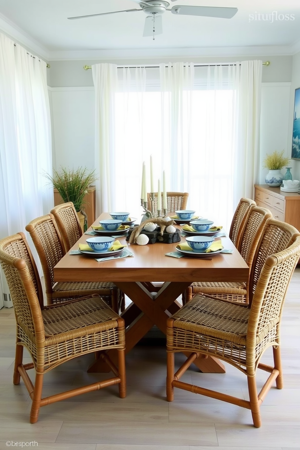 A beach-themed dining room features a light wooden table surrounded by rattan chairs. The table is set with vibrant blue and white ceramic plates, seashell-shaped bowls, and colorful napkins that evoke a coastal vibe. Soft natural light filters through sheer white curtains, illuminating the space. Decorative elements include a centerpiece of driftwood and candles, complemented by ocean-inspired artwork on the walls.