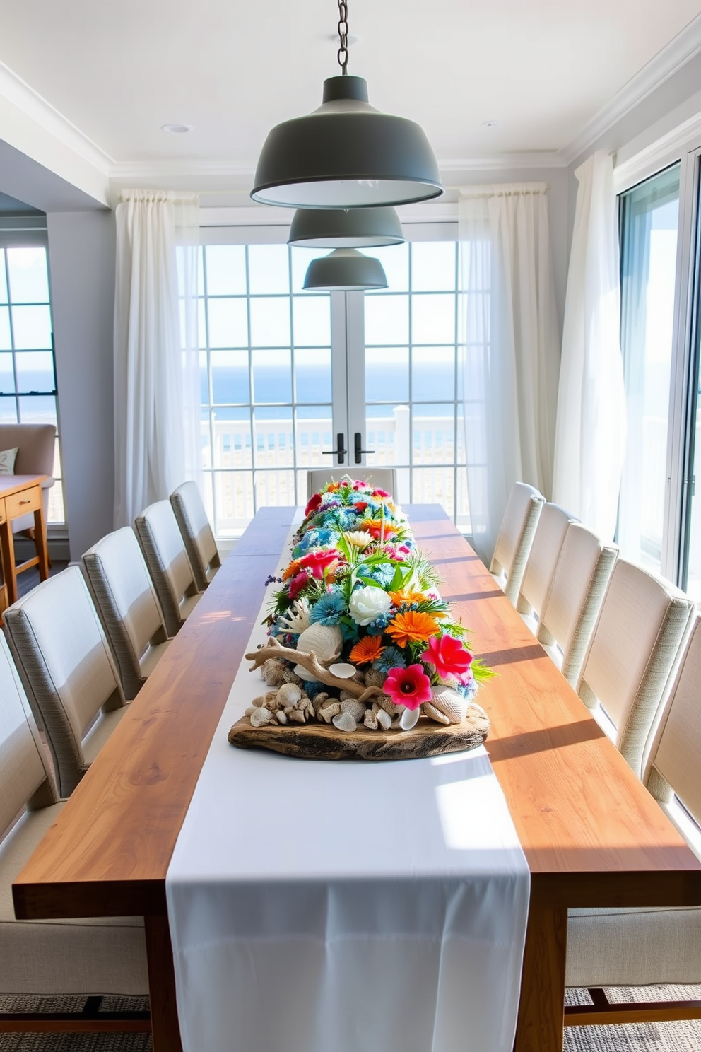 A coastal-inspired dining room features a long wooden table adorned with a crisp white tablecloth. Centered on the table is a vibrant arrangement of seashells, driftwood, and fresh flowers in shades of blue and coral. The chairs are upholstered in light linen fabric, creating a relaxed and inviting atmosphere. Large windows allow natural light to flood the space, with sheer curtains that gently sway in the ocean breeze.