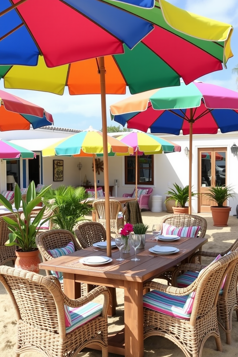 A vibrant outdoor dining area features colorful beach umbrellas providing shade over a rustic wooden table set for a summer meal. Surrounding the table are comfortable wicker chairs adorned with bright cushions, and potted plants add a touch of greenery to the sandy backdrop.