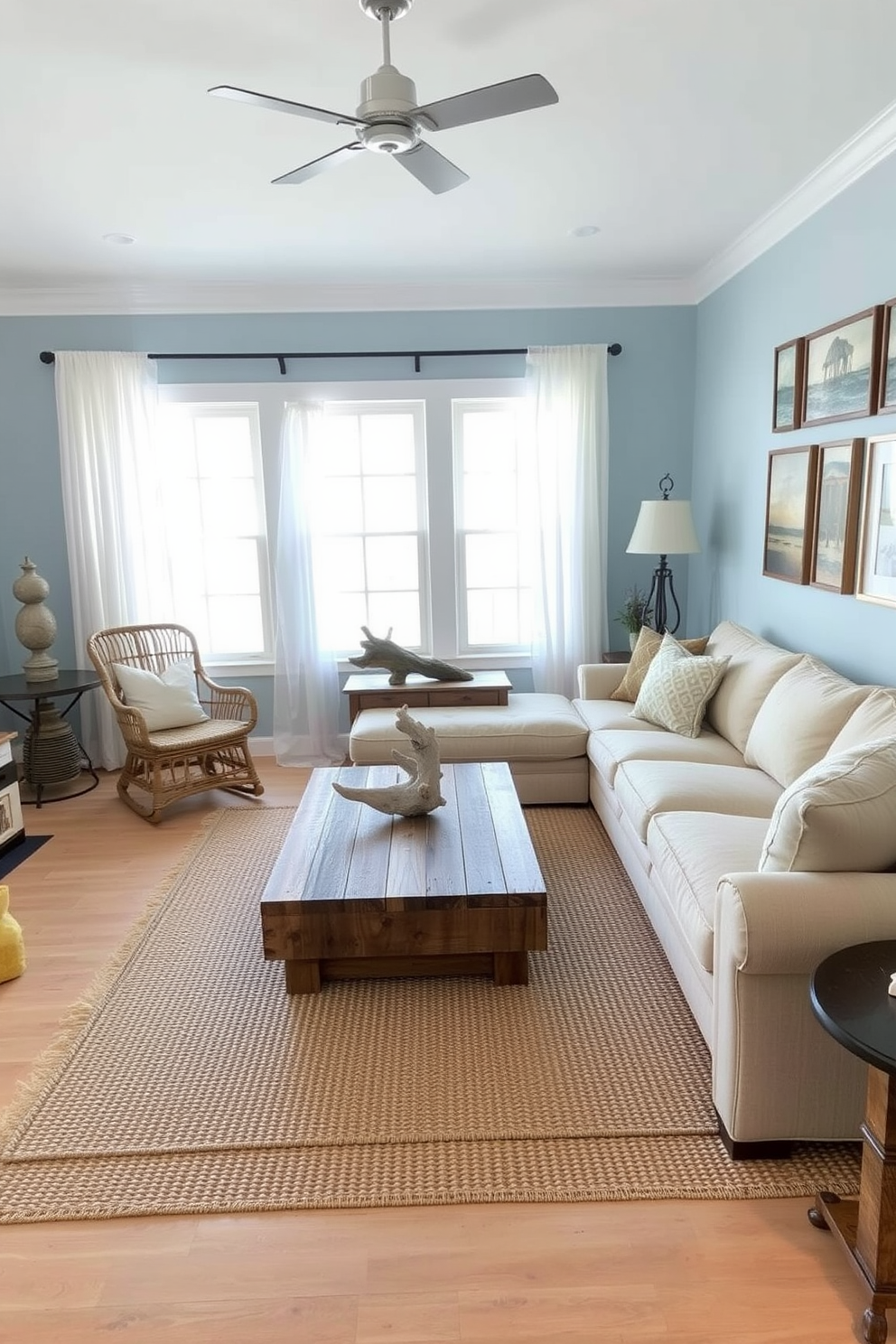 A beach living room with rustic accents features a large, comfortable sectional sofa in light beige fabric, complemented by a reclaimed wood coffee table at the center. Natural light floods the space through large windows adorned with sheer white curtains, highlighting the coastal decor and a woven area rug that adds warmth underfoot. In one corner, a pair of rattan chairs provide additional seating, while a driftwood sculpture serves as a striking focal point on a side table. The walls are painted in soft blue tones, evoking a serene seaside atmosphere, and a gallery of beach-themed artwork hangs above the sofa, tying the room together.