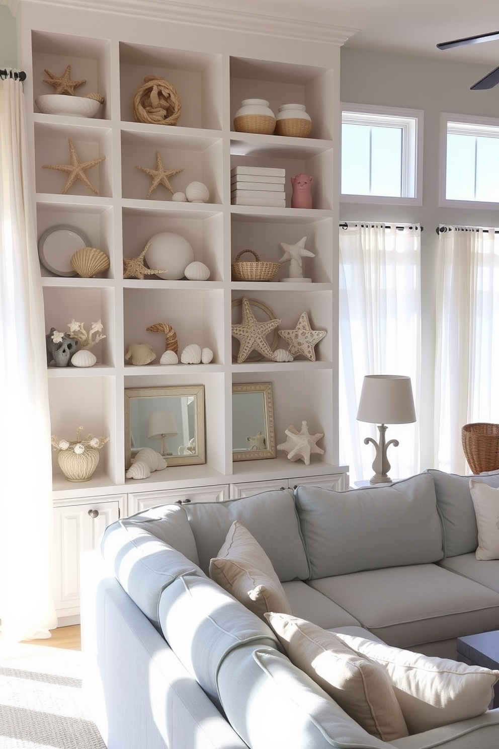 Open shelving displays an array of beach-inspired accessories including seashells, driftwood, and coral. The shelves are painted in a soft white color, creating a bright and airy feel in the room. The living room features a comfortable sectional sofa upholstered in light blue fabric. Natural light floods the space through large windows adorned with sheer white curtains, enhancing the coastal vibe.