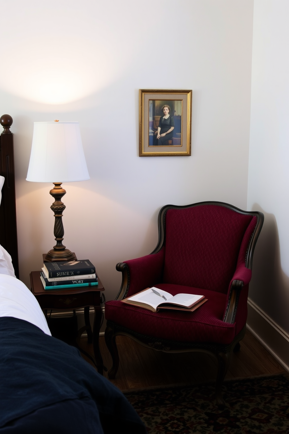 A cozy bedroom reading nook featuring a vintage armchair upholstered in a rich burgundy fabric. Beside the armchair, a small wooden side table holds a stack of books and a decorative lamp with a warm glow.