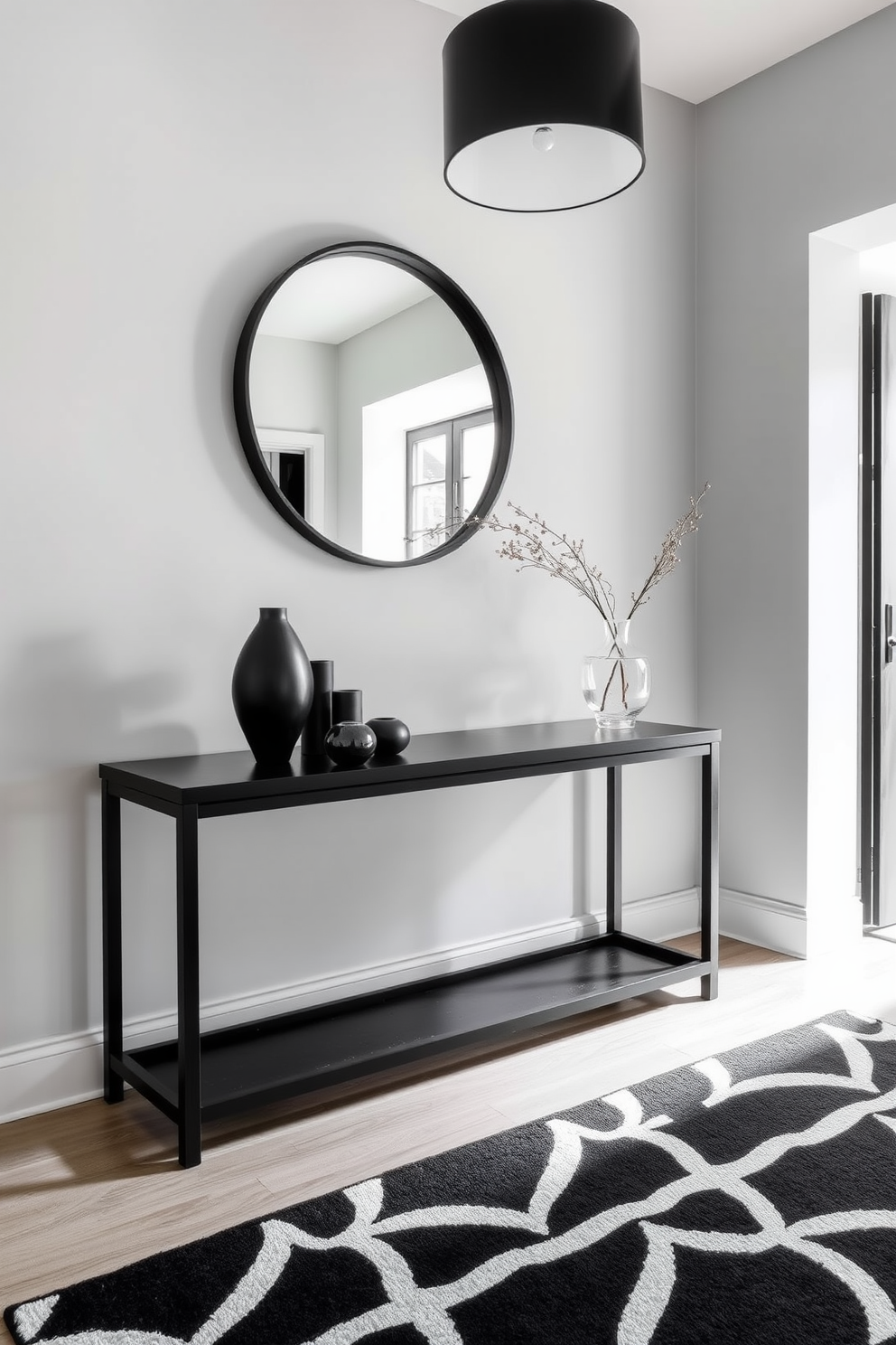 A stylish entryway featuring a sleek black console table against a light gray wall. Above the table, a large round mirror with a black frame reflects natural light, while a black and white geometric rug adds texture to the space. On the console table, a cluster of black decorative objects and a small potted plant create a modern aesthetic. The entryway is illuminated by a contemporary black pendant light hanging from the ceiling, enhancing the overall elegance of the design.