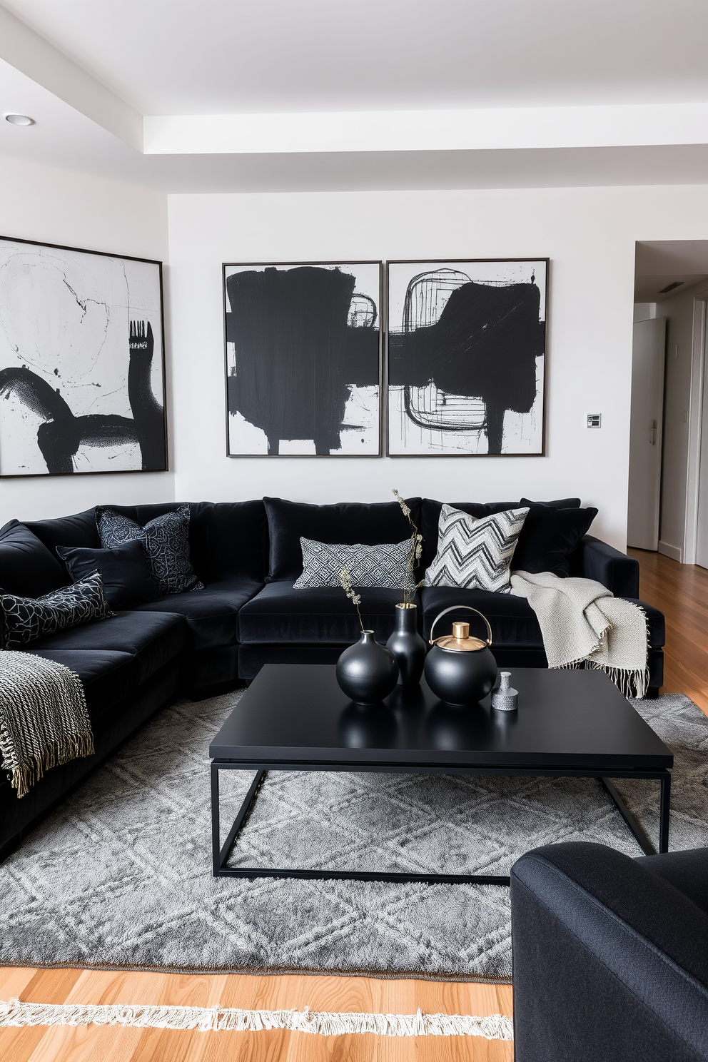 A contemporary apartment interior featuring layered textures with an emphasis on black textiles. The living room showcases a plush black velvet sofa paired with a textured woven throw and accent pillows in various black patterns. The walls are adorned with abstract black and white art, creating a striking contrast against the warm wooden floors. A sleek black coffee table sits in the center, surrounded by a mix of metallic and matte black decor elements.