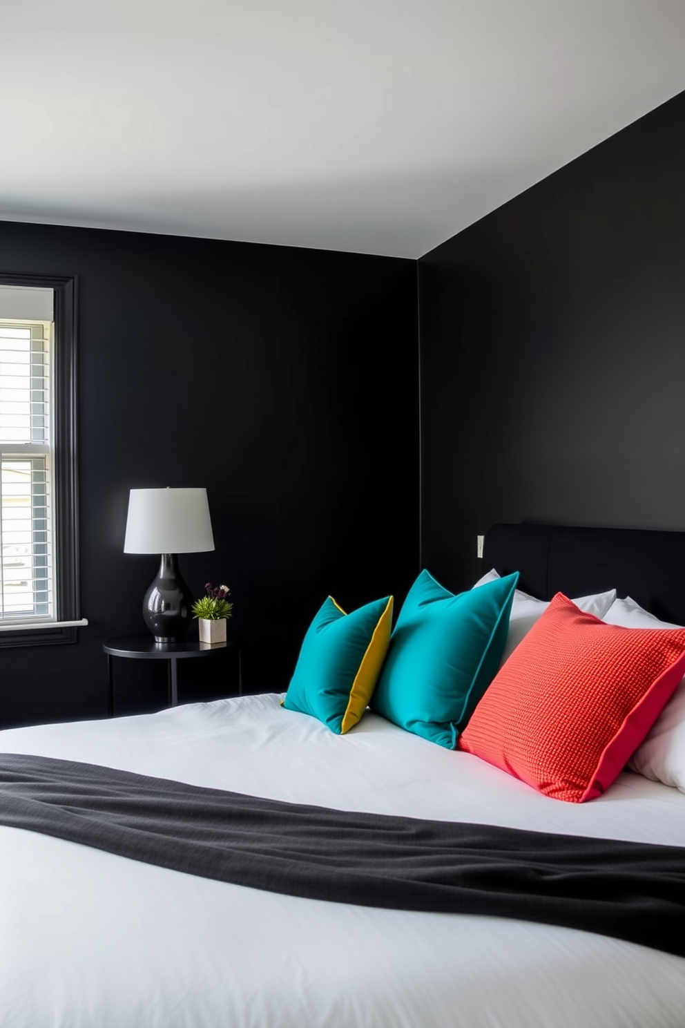 A striking black bedroom features walls painted in a deep matte black creating a bold and dramatic atmosphere. Colorful throw pillows in vibrant hues of teal, mustard, and coral adorn a plush white bed, adding a playful contrast to the dark backdrop.