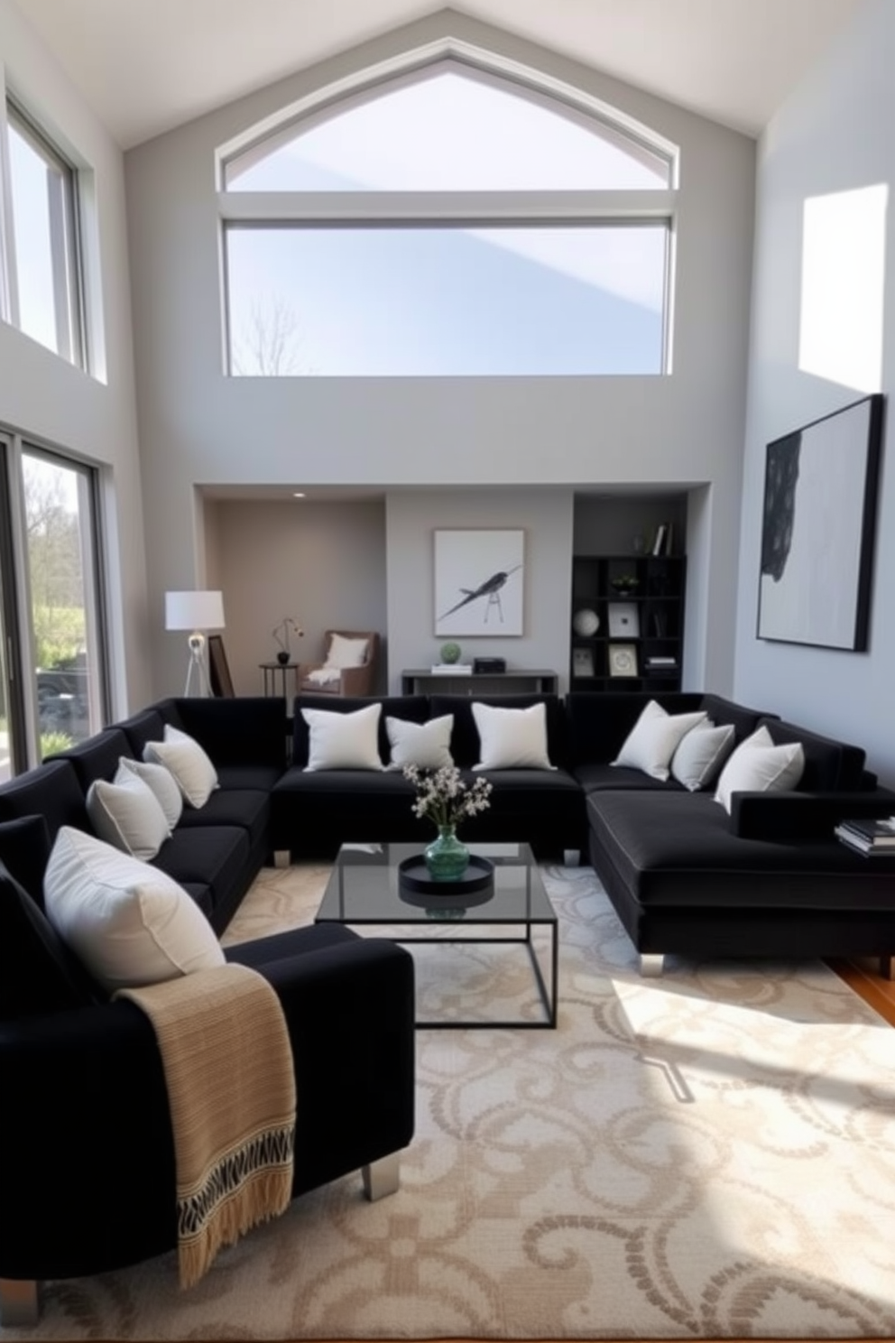 A modern family room featuring a sleek black sectional sofa adorned with contrasting white accent pillows. The walls are painted in a soft gray, and a large area rug in neutral tones anchors the space while a stylish coffee table sits at the center. Floor-to-ceiling windows allow natural light to flood the room, highlighting the minimalist decor and a statement art piece on one wall. A cozy reading nook with a plush armchair and a small bookshelf adds warmth and functionality to the design.