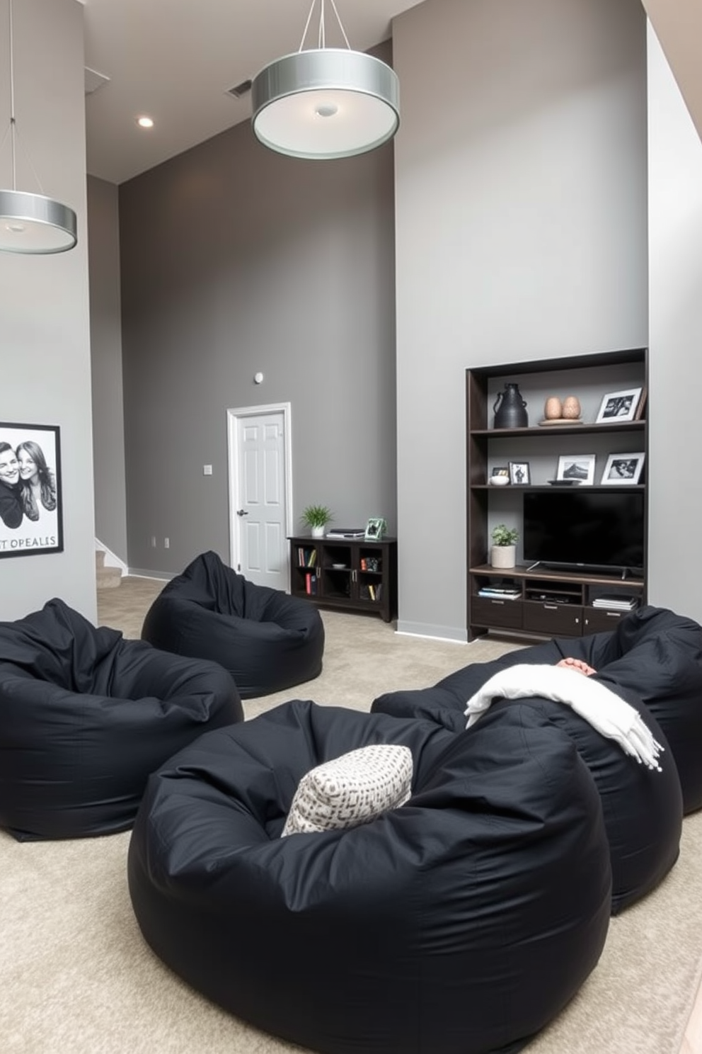 A cozy black bean bag seating area is arranged in a spacious family room. The walls are painted in a soft gray, complementing the black bean bags and creating an inviting atmosphere. A large entertainment unit is positioned against one wall, adorned with decorative items and family photos. Soft lighting fixtures hang from the ceiling, enhancing the room's warmth and comfort.