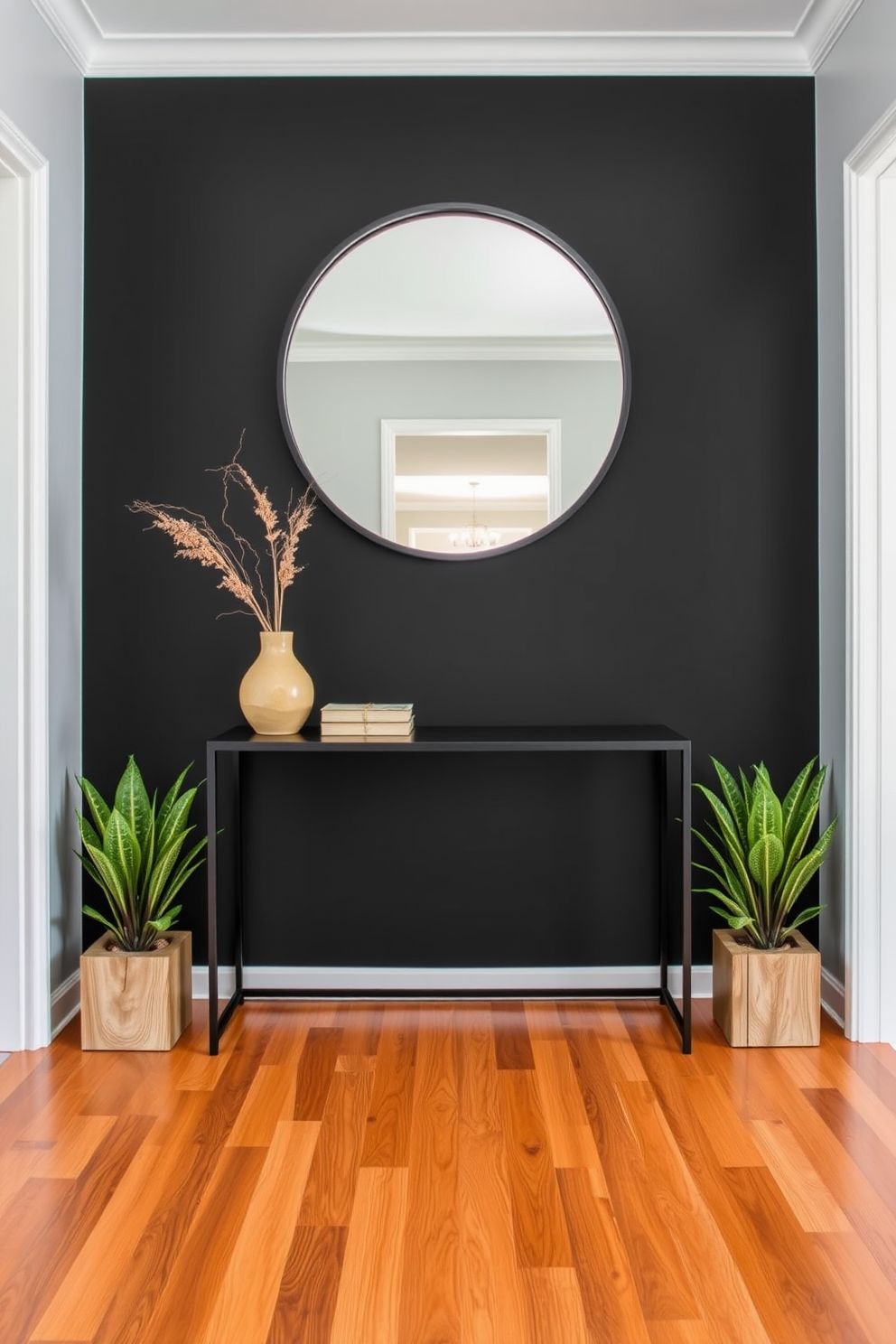 A striking foyer design featuring a bold black accent wall paired with natural wood elements. The floor is adorned with a rich wooden finish that complements the sleek black console table positioned against the wall. A large round mirror with a black frame hangs above the console, reflecting the warm tones of the wood. Decorative plants in natural wood planters are placed on either side of the console, adding a touch of greenery to the space.