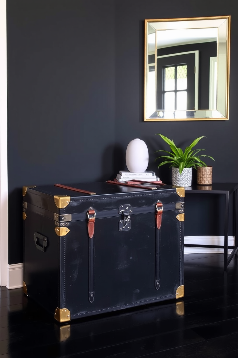 A vintage black trunk sits prominently in the foyer, serving as both a stylish storage solution and a conversation piece. The trunk is adorned with brass accents and leather straps, adding character to the space. The foyer features a sleek black color palette, with a statement mirror above a minimalist console table. Complementing the trunk, potted greenery adds a touch of freshness against the dark tones.