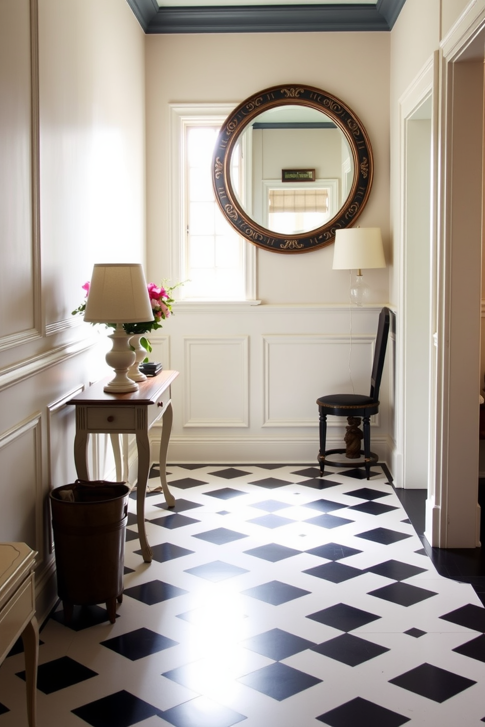 A charming foyer features a striking black and white checkered floor that creates a bold visual impact. The walls are adorned with elegant wainscoting painted in a soft cream color, enhancing the classic aesthetic of the space. A vintage console table sits against one wall, topped with a stylish lamp and an arrangement of fresh flowers. Above the table, a large round mirror with a decorative frame reflects the natural light streaming in from a nearby window.