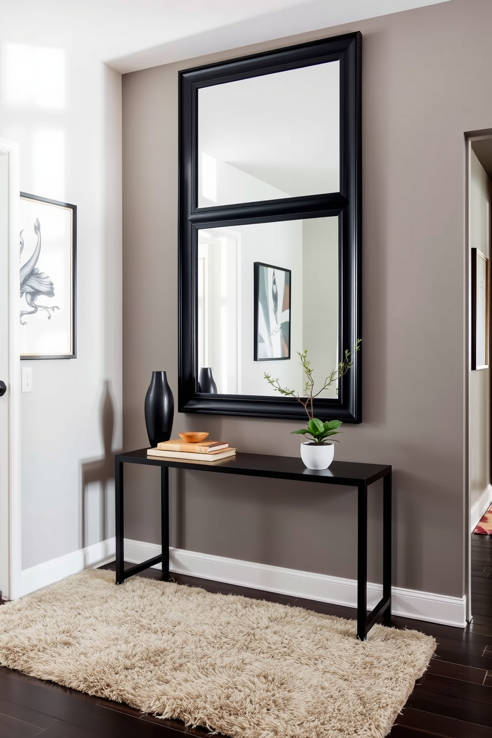 A stylish black mirror is positioned in a well-lit foyer, reflecting natural light and enhancing the spacious feel of the entryway. The walls are adorned with elegant artwork, and a sleek console table below the mirror holds decorative items and a small plant. The foyer features a sophisticated color palette with deep hues and warm accents, creating an inviting atmosphere. A plush area rug lies beneath the console table, adding texture and comfort to the space.