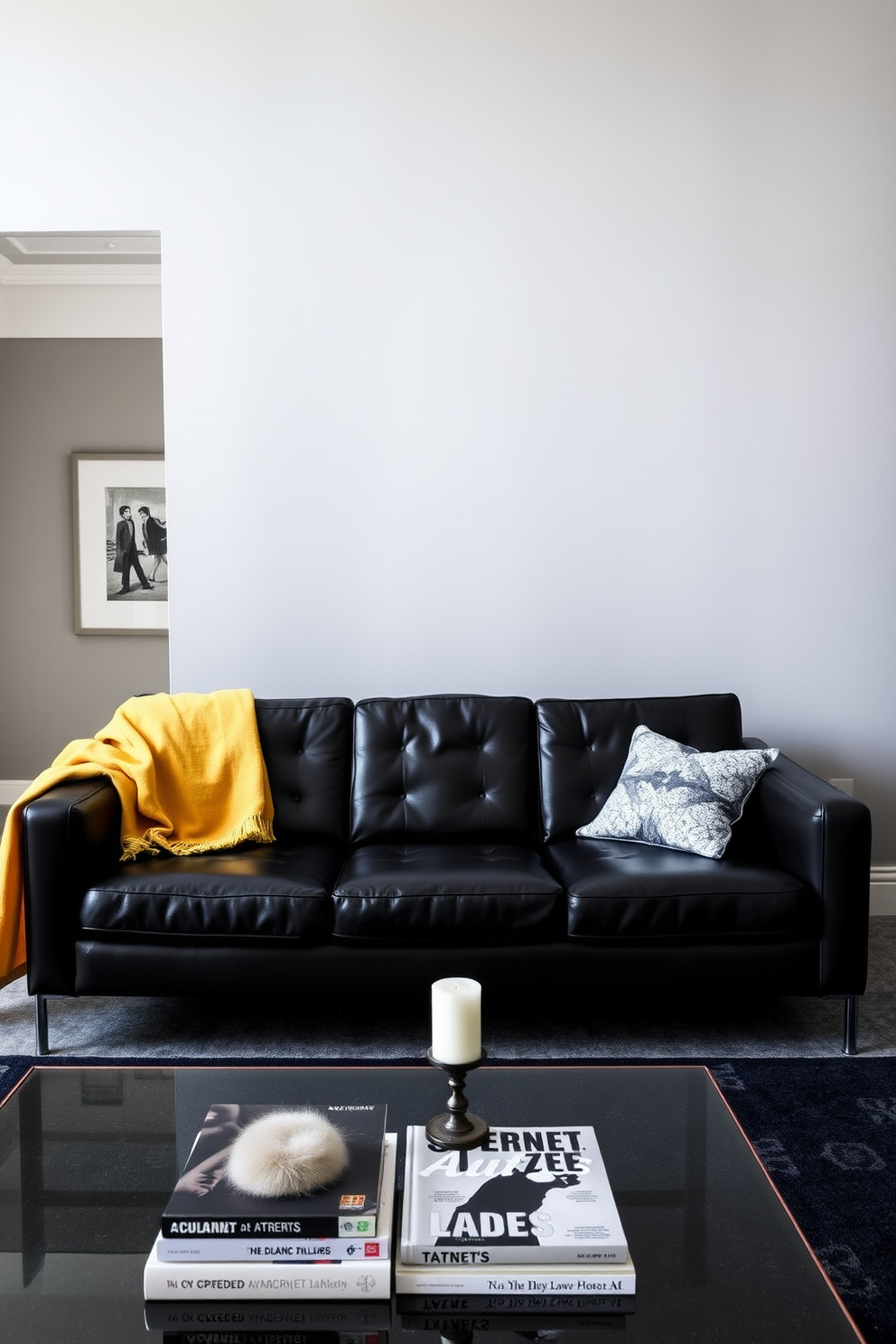 A sleek black leather sofa is positioned in the center of the room, complemented by a vibrant throw draped casually over one arm. The walls are painted in a soft gray, enhancing the modern aesthetic while a stylish coffee table sits in front of the sofa, adorned with art books and a decorative candle.