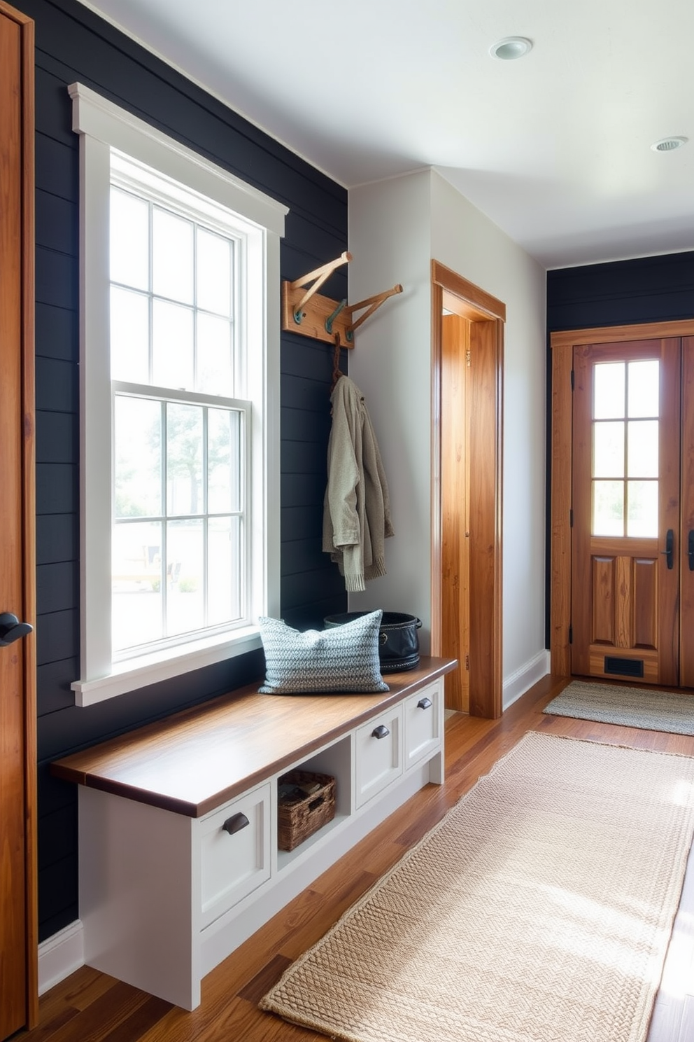 A mudroom with black shiplap walls creates a striking contrast against rustic wooden accents. The space features a built-in bench with storage underneath and hooks above for hanging coats and bags. Natural light floods the area through a large window, highlighting the warm tones of the wood. A woven rug adds texture and warmth to the floor, completing the inviting atmosphere.