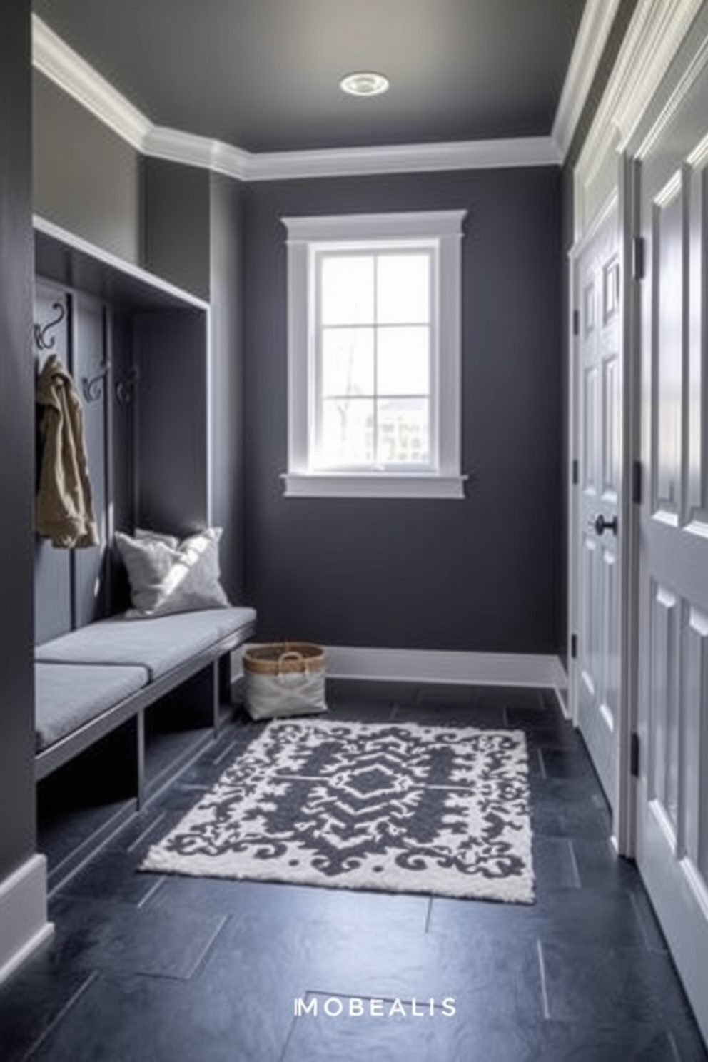 A stylish mudroom featuring a black and gray color palette. The walls are painted a deep charcoal gray while the floor is covered with sleek black tiles. A custom-built bench with gray cushions sits against the wall, complemented by black hooks for coats and bags. Natural light filters in through a large window, illuminating a decorative black and white rug on the floor.