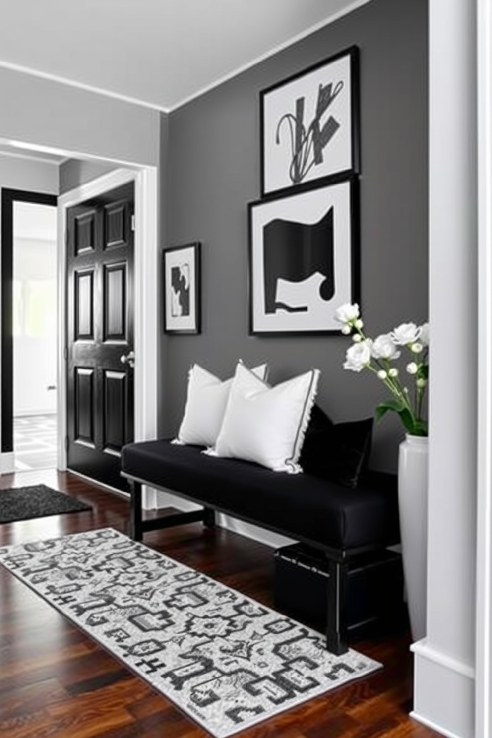 A stylish black and white entryway features a sleek bench upholstered in a chic black fabric with white accent pillows. The walls are adorned with black and white artwork, and a patterned rug adds a touch of elegance to the space.