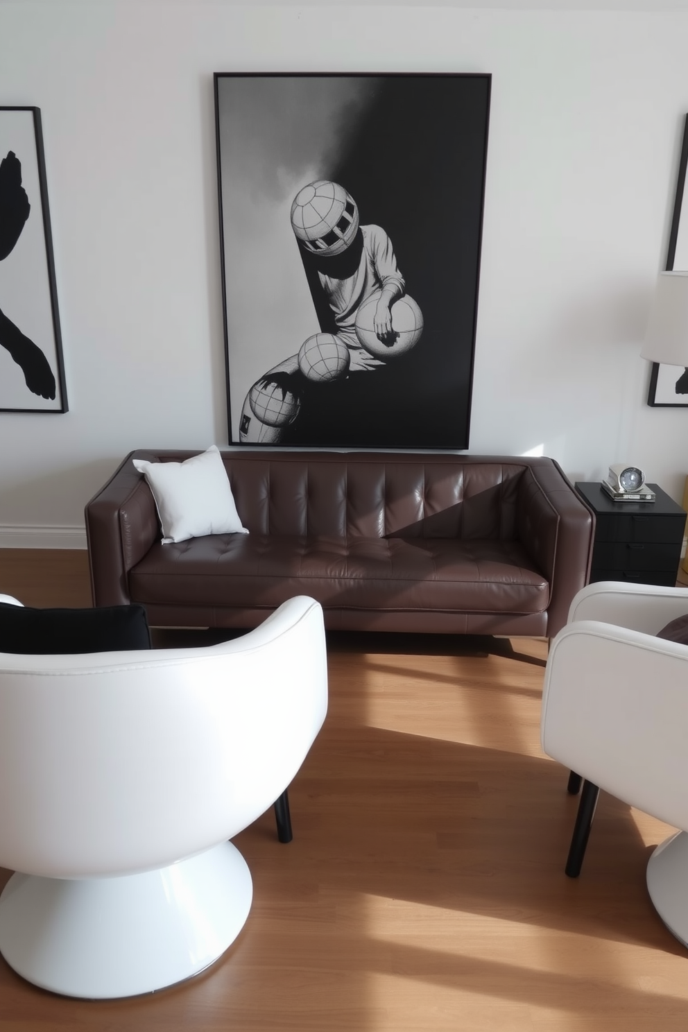 A sleek leather sofa is positioned centrally in the room, complemented by two white accent chairs on either side. The walls are adorned with black and white artwork, creating a striking contrast that enhances the modern aesthetic.