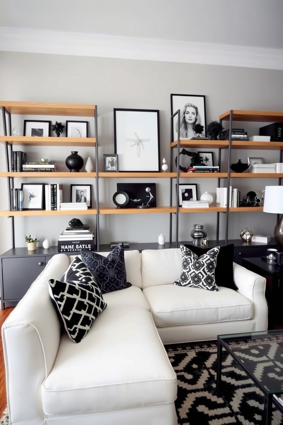 A stylish living room featuring open shelving adorned with black and white decor. The shelves display a mix of art pieces, books, and decorative objects, creating a harmonious balance in the space. The walls are painted in a soft gray, providing a neutral backdrop for the bold black and white accents. A plush white sofa is positioned in front of the shelving, complemented by black and white patterned throw pillows and a geometric area rug.