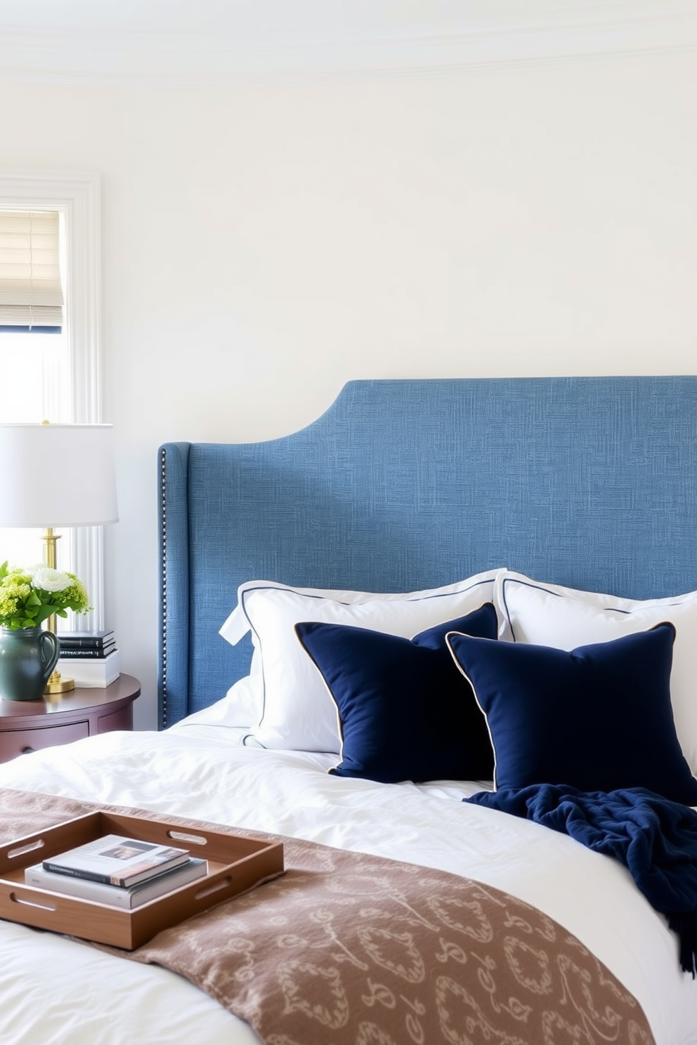 A cozy bedroom featuring a denim blue upholstered headboard that adds comfort and style. The walls are painted in a soft white, complemented by navy blue accents in the bedding and decor.