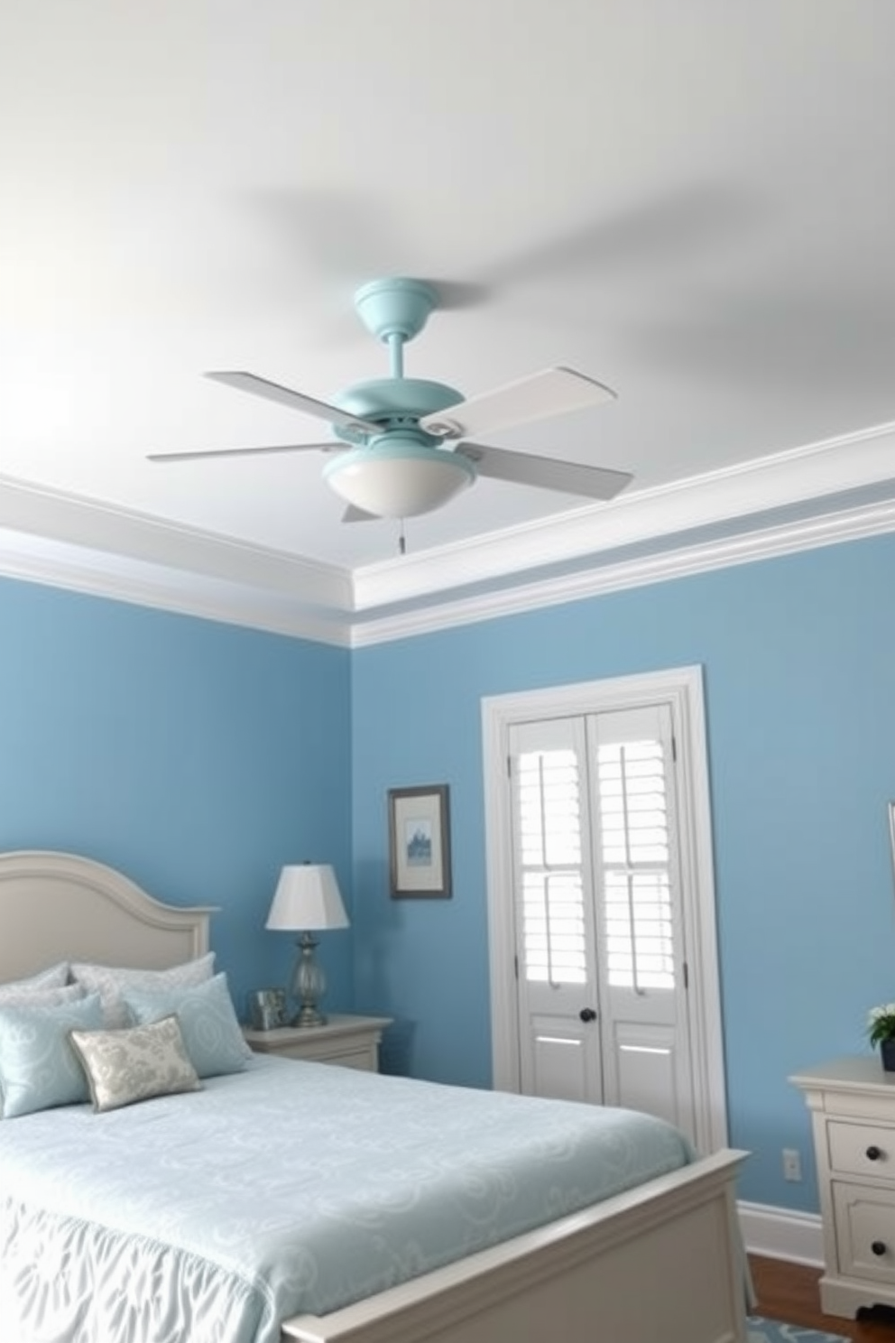 A serene blue bedroom with a pale blue ceiling fan that enhances the room's functionality. The walls are painted in a soft blue hue, complemented by white trim and elegant furnishings.