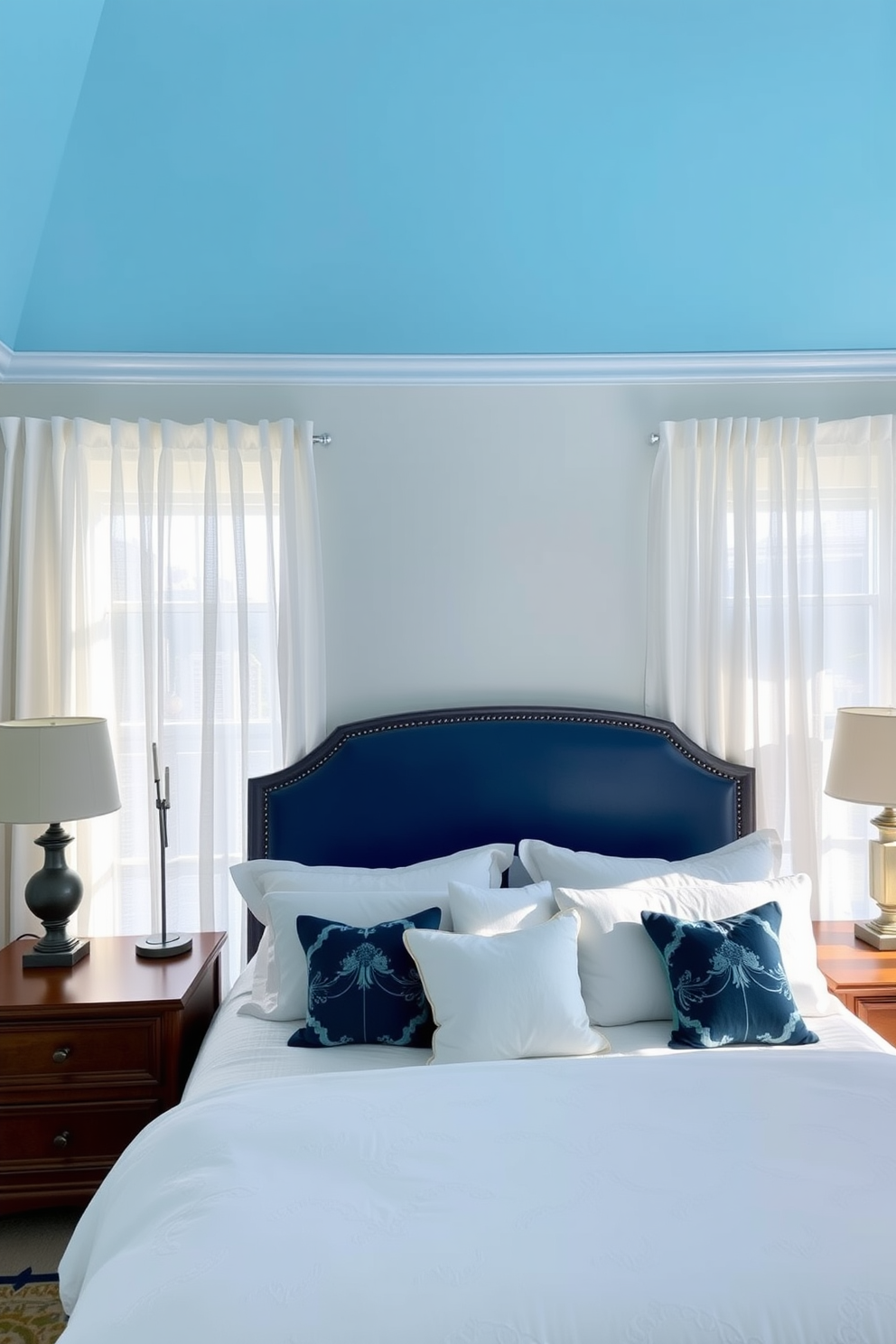 Sky blue painted ceiling enhances the sense of height in the room. The bedroom features a cozy king-sized bed with plush white bedding and decorative throw pillows in varying shades of blue. Soft natural light filters through sheer white curtains, creating a serene atmosphere. A stylish wooden nightstand on either side of the bed holds elegant lamps that add warmth to the space.