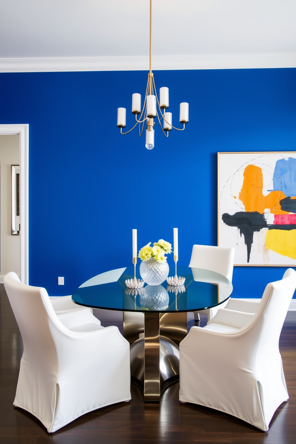 A bold royal blue statement wall creates a striking focal point in the dining room. The room features a sleek glass dining table surrounded by elegant white upholstered chairs that complement the vibrant wall color. The lighting is provided by a modern chandelier with metallic accents, casting a warm glow over the space. To enhance the decor, a large abstract artwork in contrasting colors is displayed on the adjacent wall, adding depth and interest.