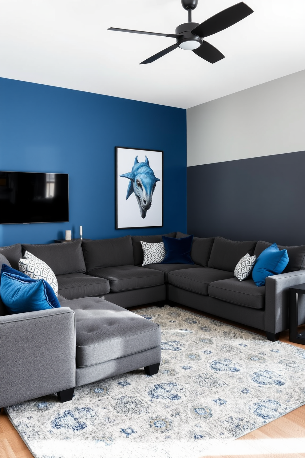 A modern family room with blue and gray color-blocked walls creating a striking visual contrast. The space features a plush gray sectional sofa adorned with blue accent pillows and a large area rug that ties the colors together.