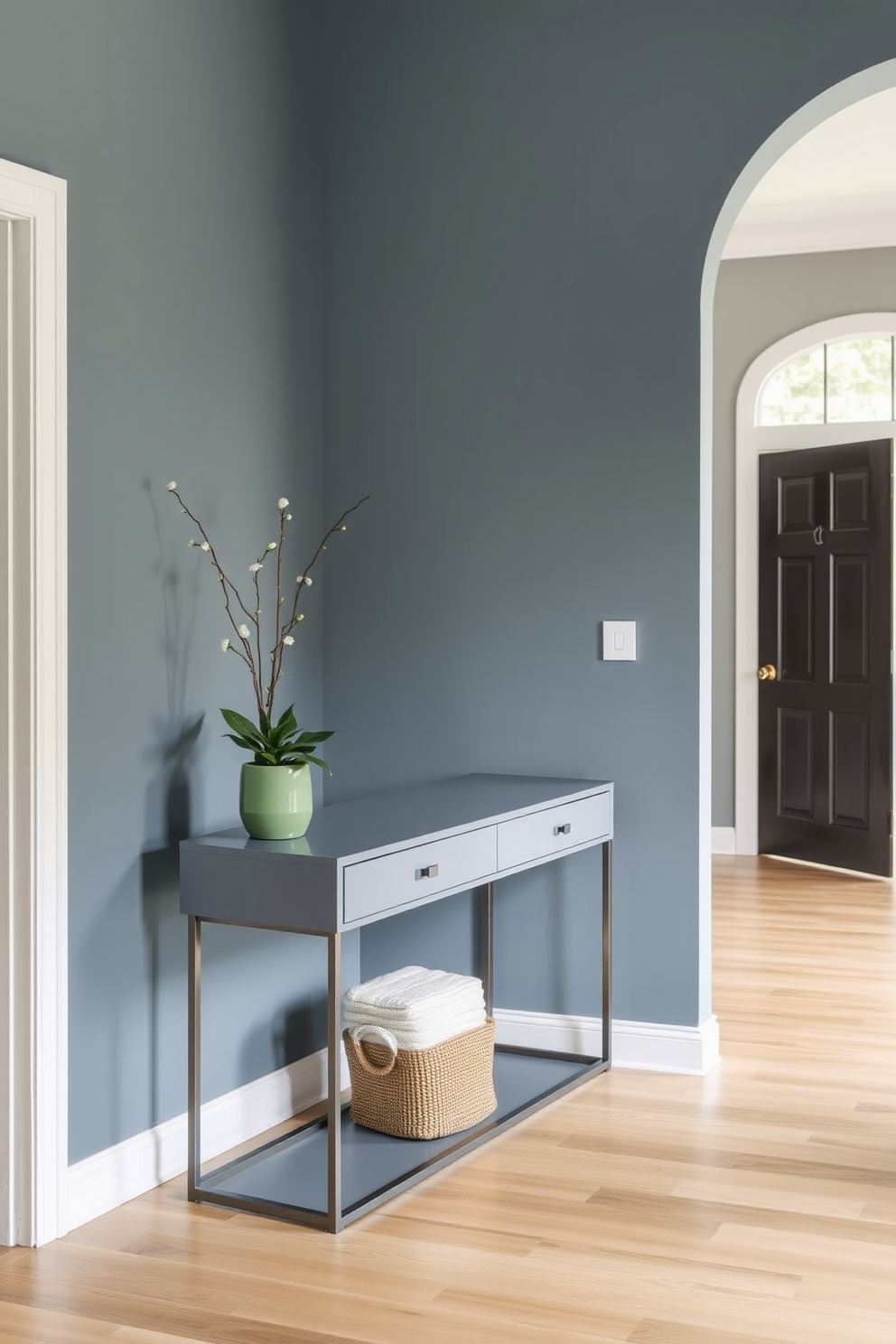 A serene foyer space featuring muted denim blue paint on the walls to create a calm and inviting atmosphere. The design includes a sleek console table with a minimalist design, adorned with a decorative mirror and a small potted plant for a touch of greenery.