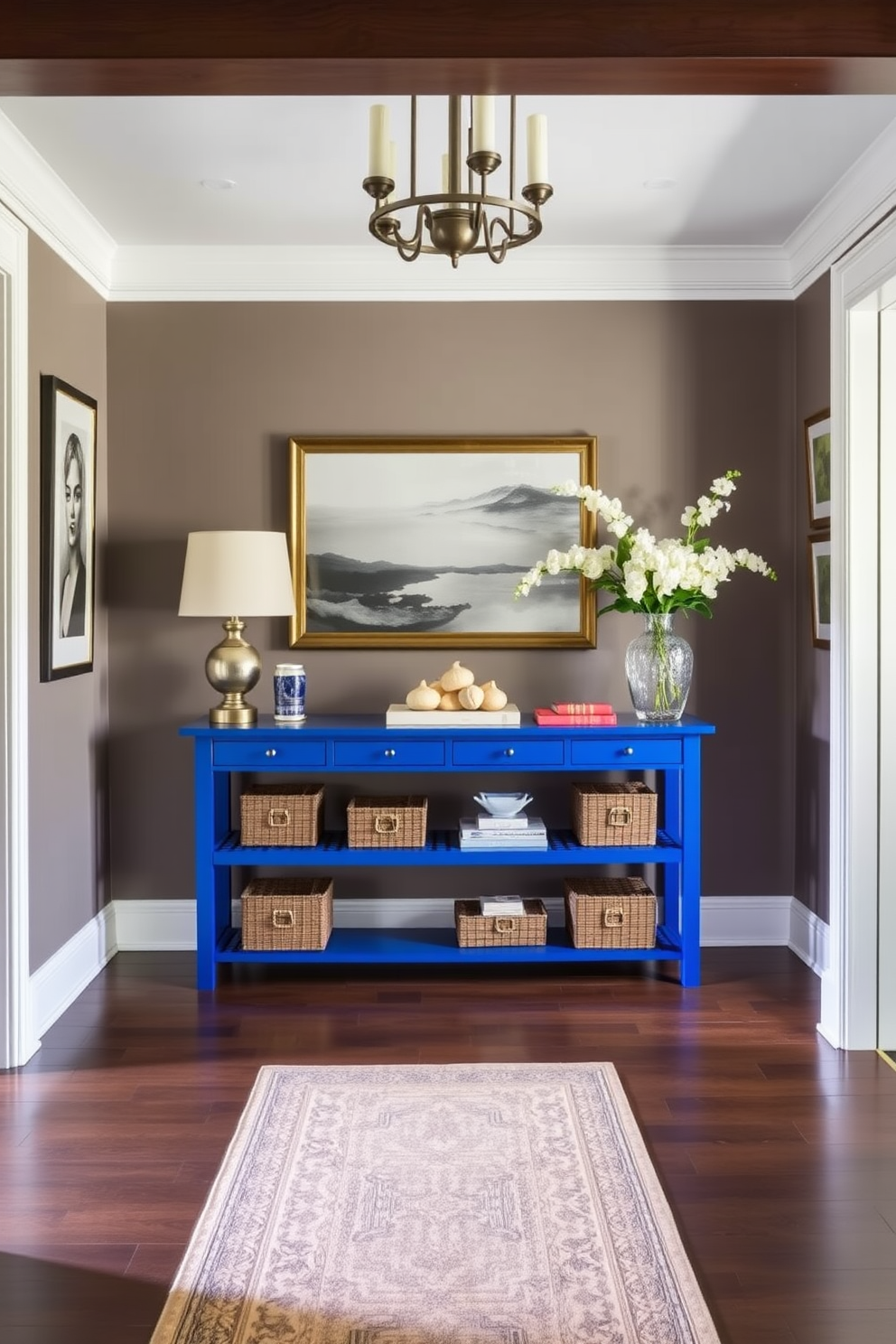 A stunning foyer featuring sky blue wallpaper adorned with delicate floral patterns. The space is illuminated by a modern chandelier, creating a warm and inviting atmosphere. A sleek console table made of light wood sits against the wall, topped with a decorative mirror and a vase of fresh flowers. The floor is covered with a soft cream-colored rug that adds texture and comfort to the entryway.