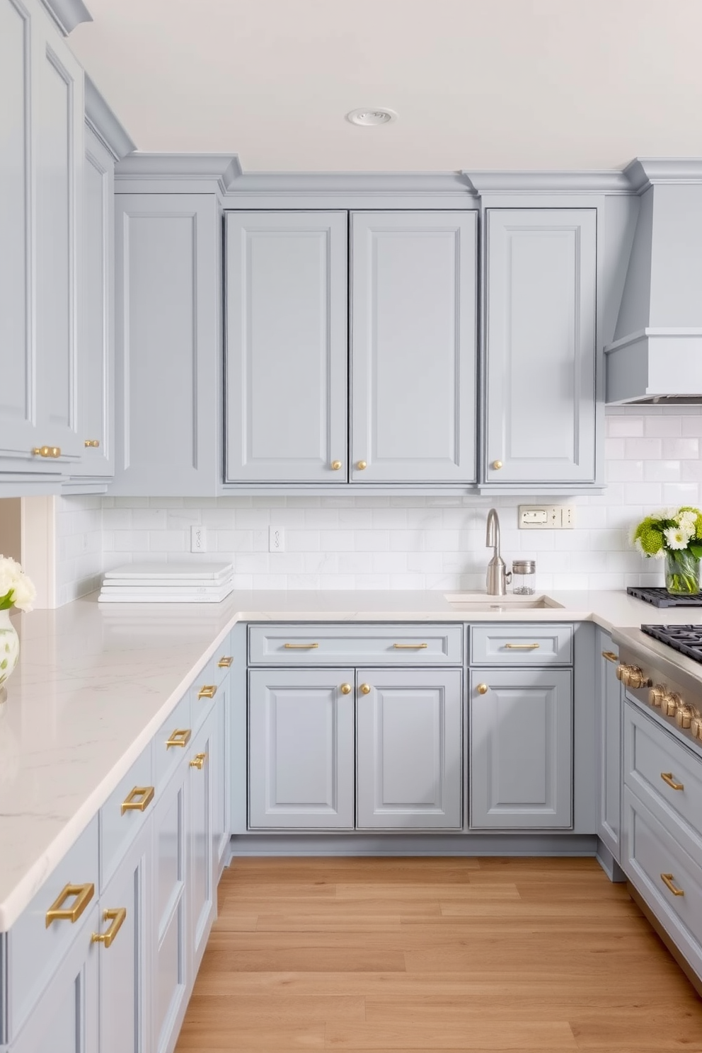 A serene kitchen space featuring dusty blue cabinets that create a calming atmosphere. The cabinets are complemented by brass hardware and white marble countertops, enhancing the elegant feel of the room.