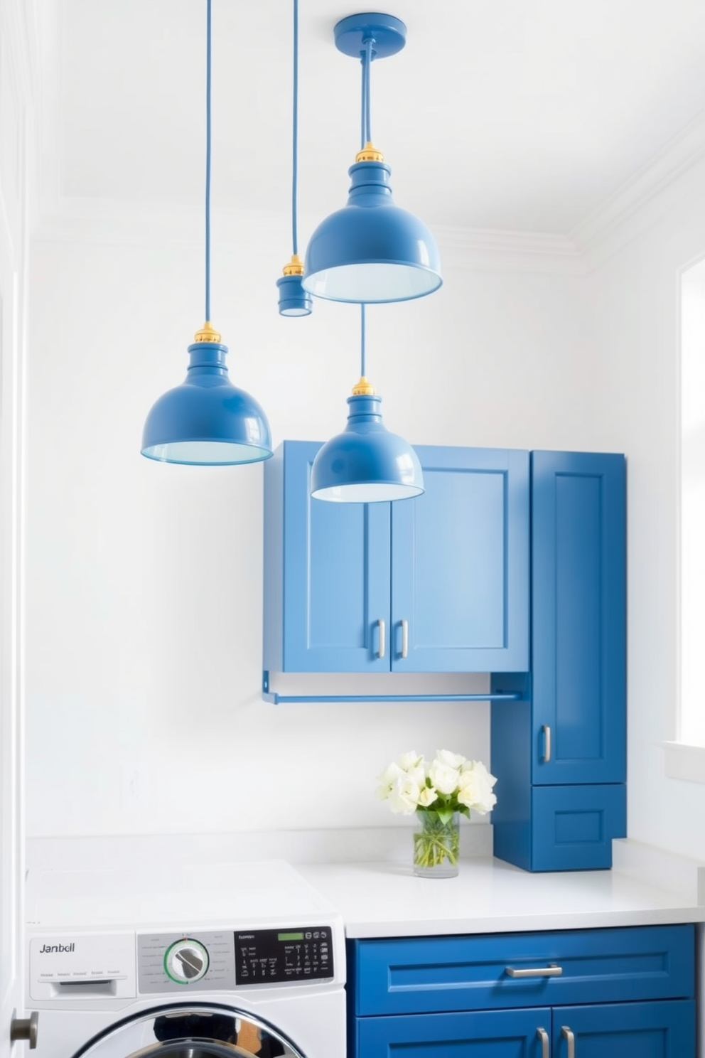 A bright and airy laundry room features blue pendant lights hanging gracefully from the ceiling, providing stylish illumination. The walls are painted a soft white, complementing the blue cabinetry and creating a fresh and inviting atmosphere.