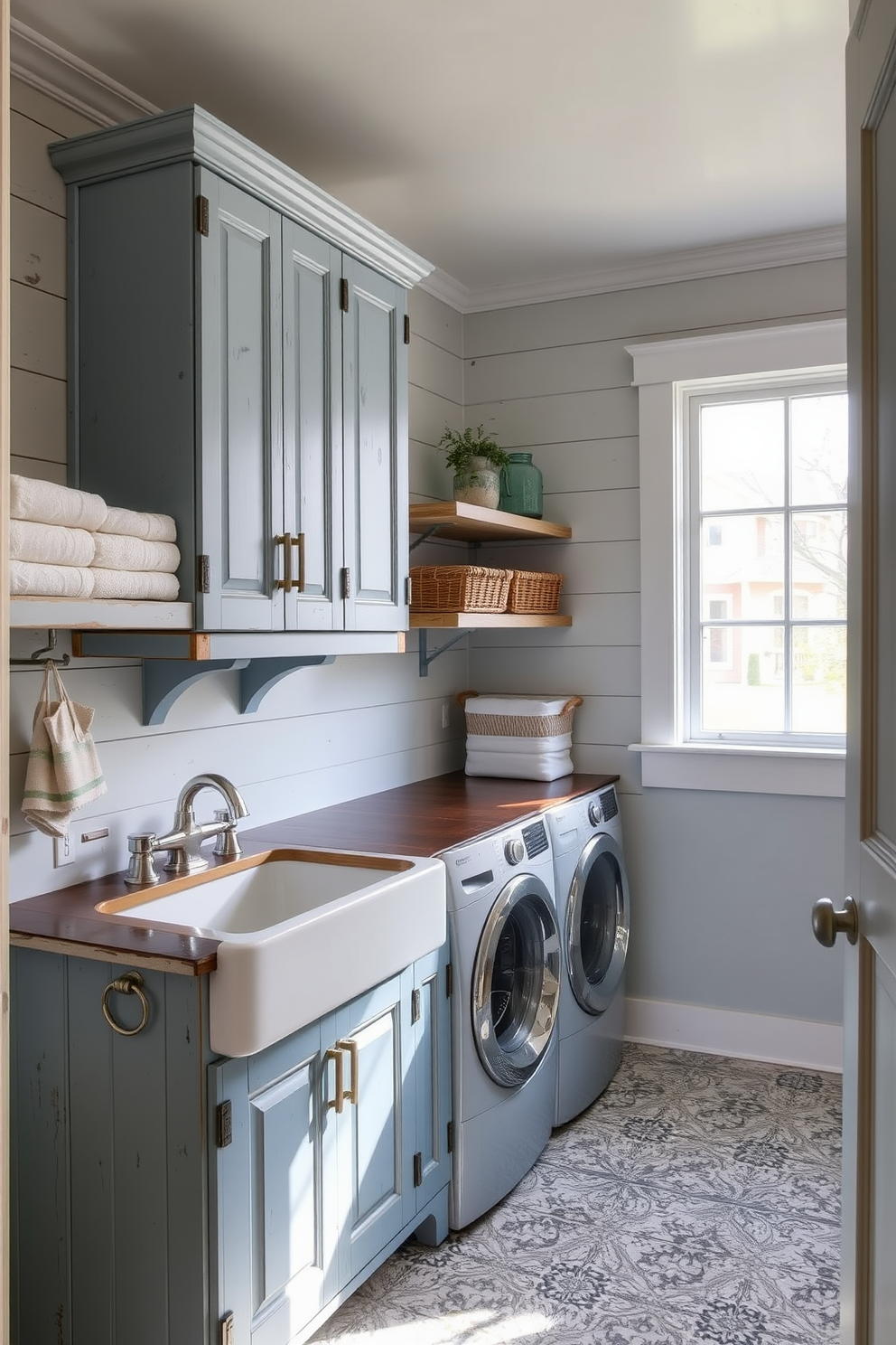 A vintage farmhouse laundry room features distressed wooden cabinets painted in a soft blue hue. The space is accented with shiplap walls, a farmhouse sink, and vintage-style hardware for a charming touch. The floor is adorned with rustic tiles that complement the blue decor, while open shelving displays neatly folded towels and decorative baskets. A large window allows natural light to flood the room, enhancing the cozy atmosphere.