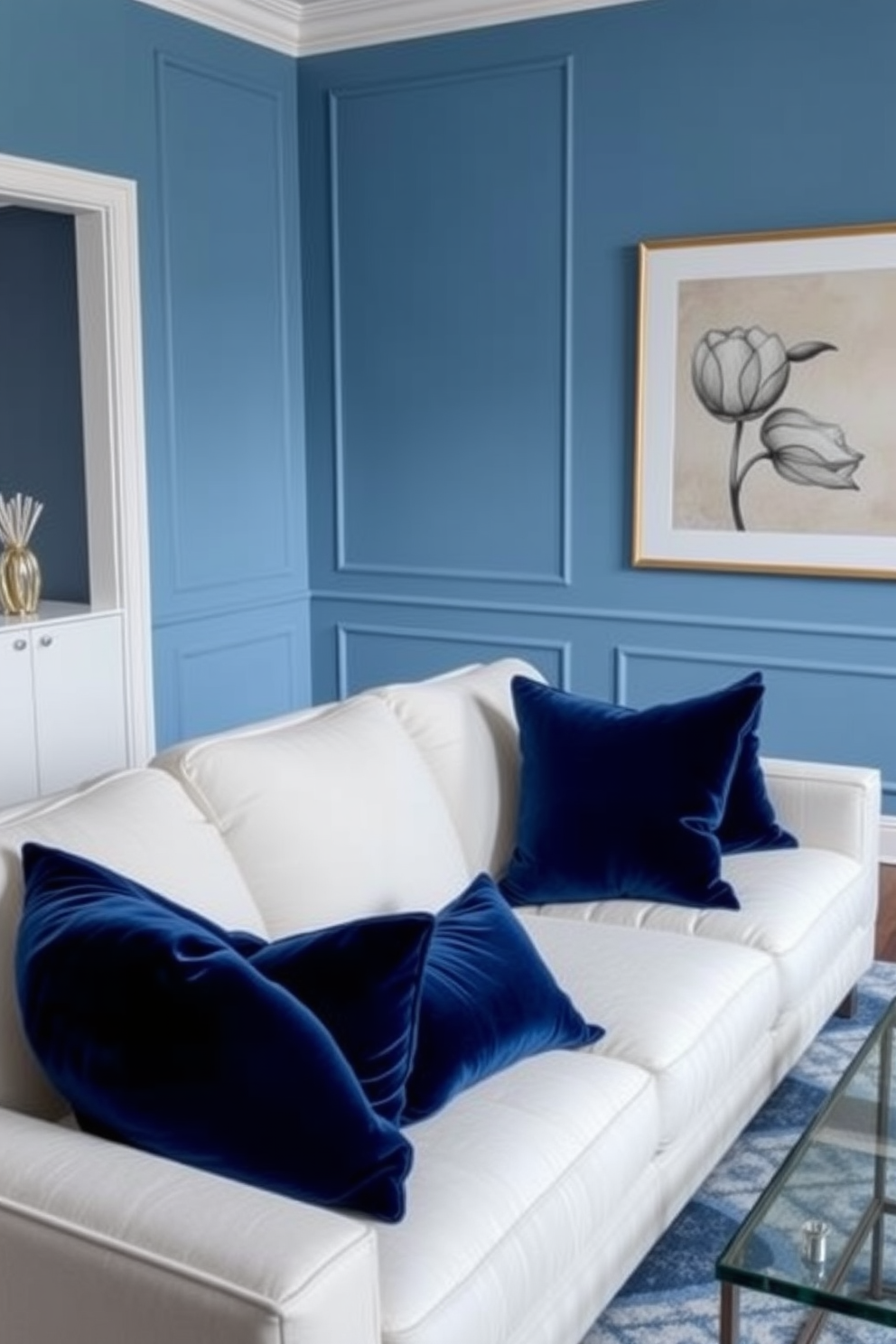 Luxe navy velvet cushions adorn a plush white sofa in a contemporary blue living room. The walls are painted in a soft sky blue, creating a serene atmosphere complemented by a sleek glass coffee table.