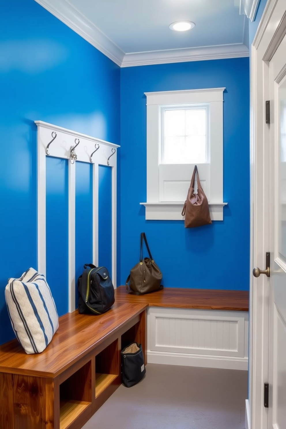 A stylish mudroom featuring cobalt blue hooks for coats and bags mounted on a light gray wall. The floor is adorned with a durable patterned tile that complements the blue accents, creating a welcoming and functional space.