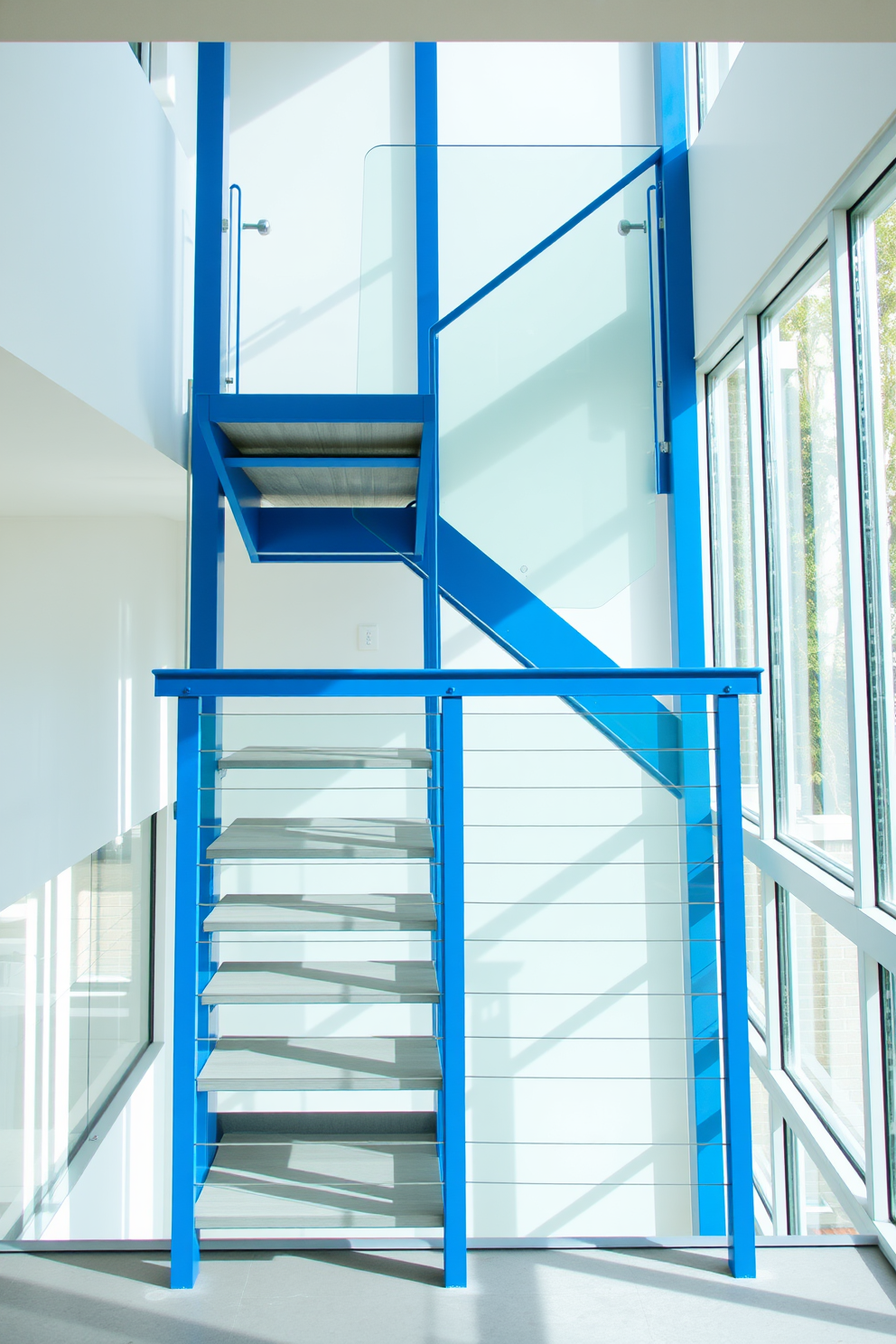 A stunning staircase adorned with blue and white striped wallpaper creates a vibrant focal point in the entryway. The blue staircase features elegant wooden steps that complement the wallpaper, enhancing the overall aesthetic of the space. The design incorporates a sleek railing that adds a modern touch while maintaining safety and style. Natural light floods the area, highlighting the beautiful contrast between the blue tones and the white accents throughout the staircase.