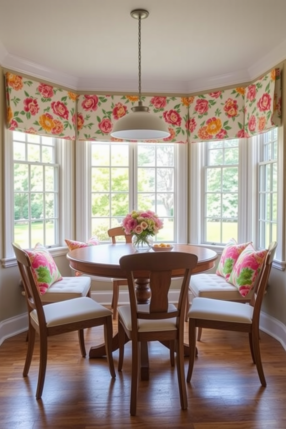 A bright and cheerful breakfast nook featuring a round wooden table surrounded by upholstered chairs. The chairs are adorned with vibrant floral cushions, and the windows are dressed with matching floral curtains that allow natural light to fill the space.