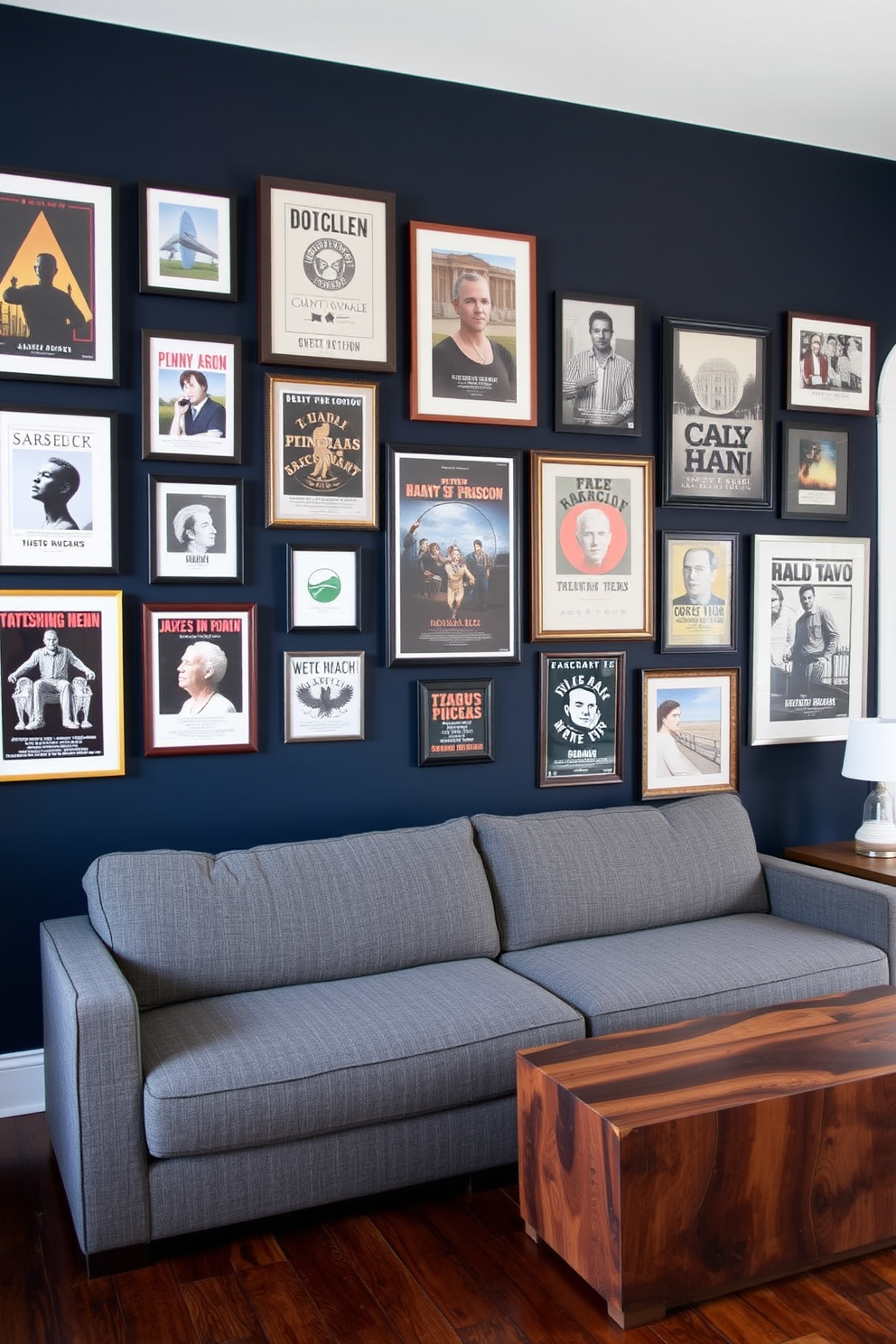 A gallery wall featuring a curated collection of framed posters in various sizes and styles. The wall is painted in a deep navy blue color to create a striking backdrop for the artwork. In the center of the space, a comfortable sectional sofa in a rich gray fabric invites relaxation. Surrounding the sofa are accent tables made of reclaimed wood, adding a rustic touch to the modern design.