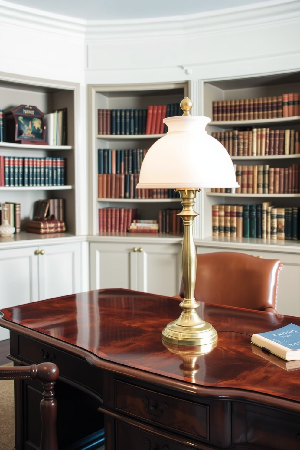 A traditional desk lamp stands elegantly on a polished wooden desk, casting a warm glow over the workspace. The lamp features a brass finish and a frosted glass shade, complementing the rich tones of the mahogany furniture. The home office is designed with classic elements, including a leather-bound chair and built-in bookshelves filled with vintage books. Soft, neutral tones adorn the walls, creating a serene environment ideal for productivity.